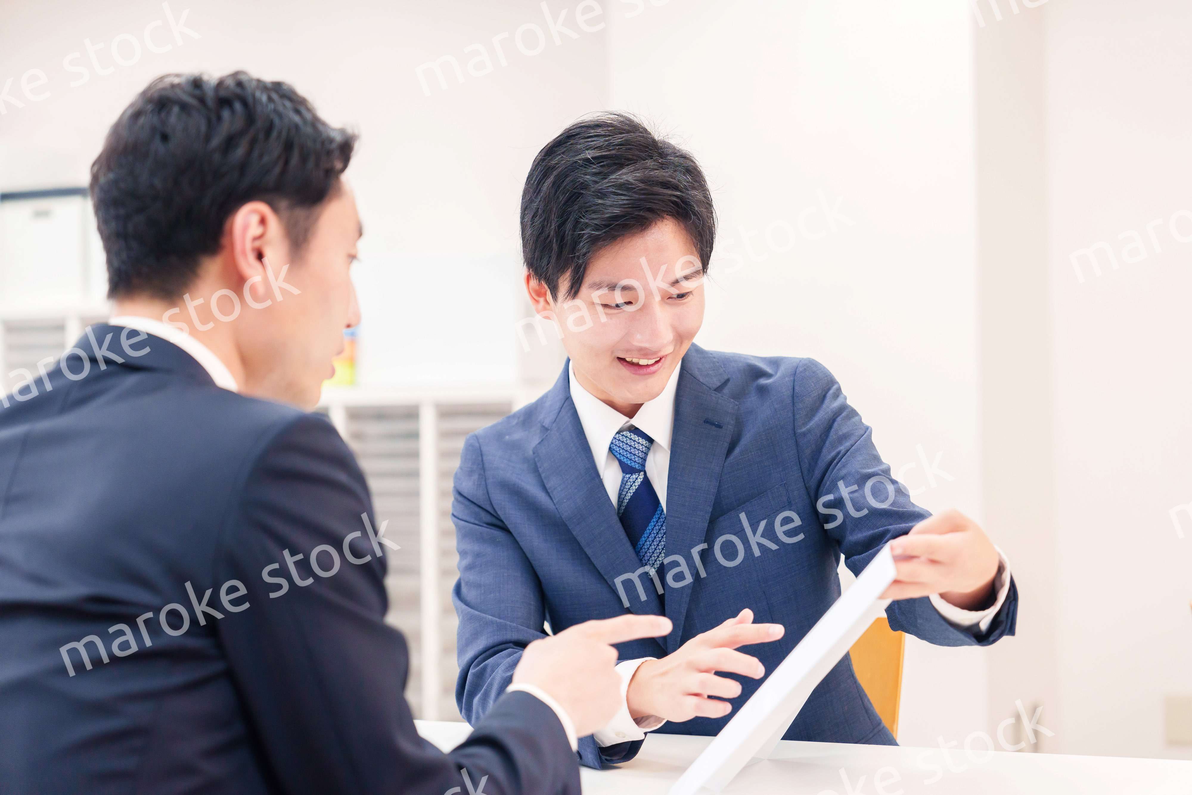 窓口で来客の対応をするビジネスマン