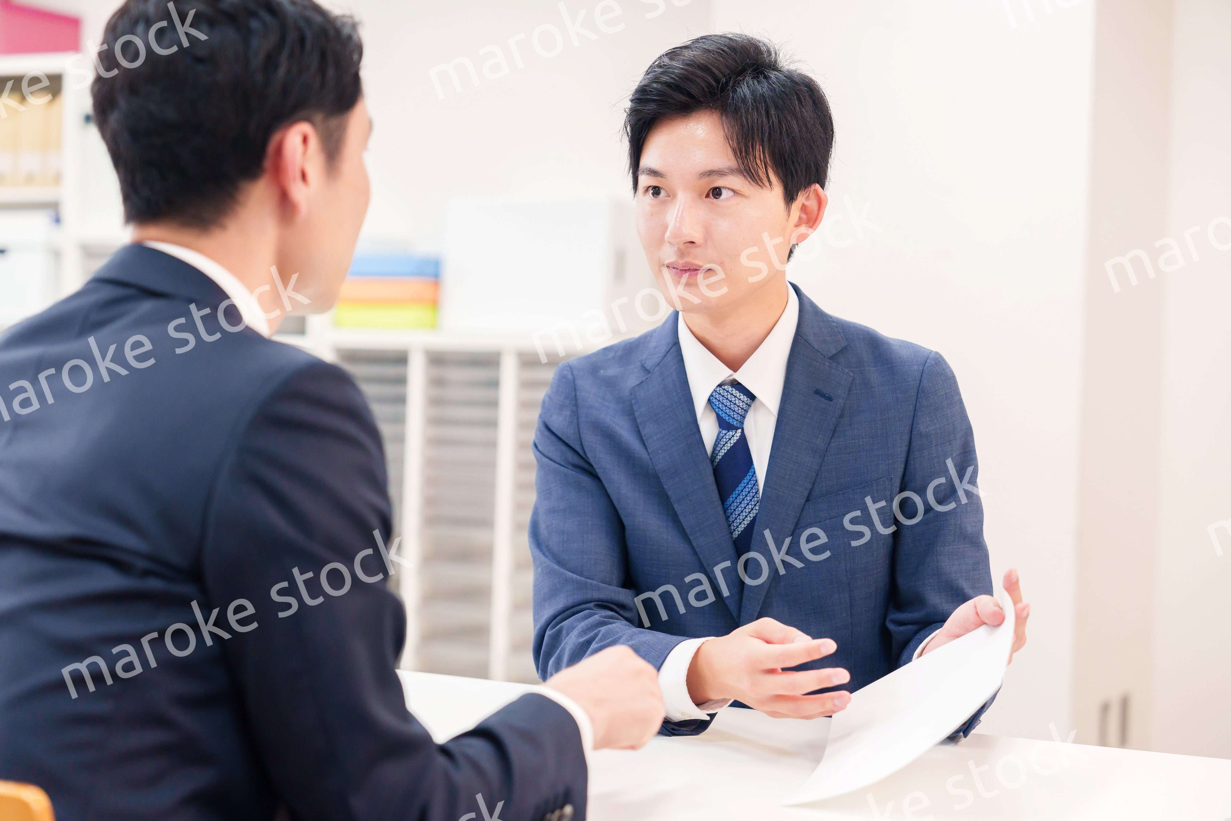 窓口で来客の対応をするビジネスマン