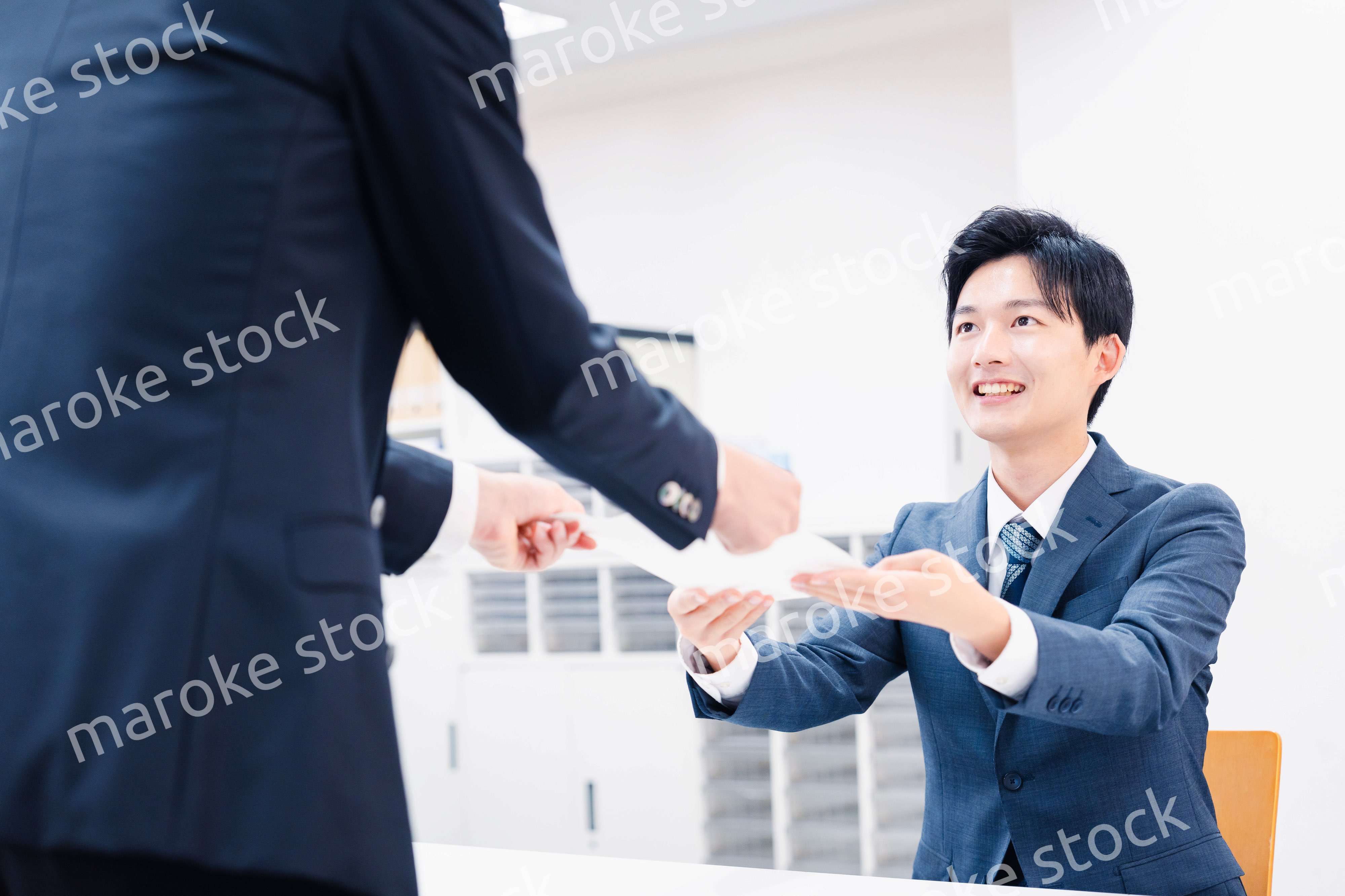 窓口で紙の書面の取り交わしをするビジネスマン