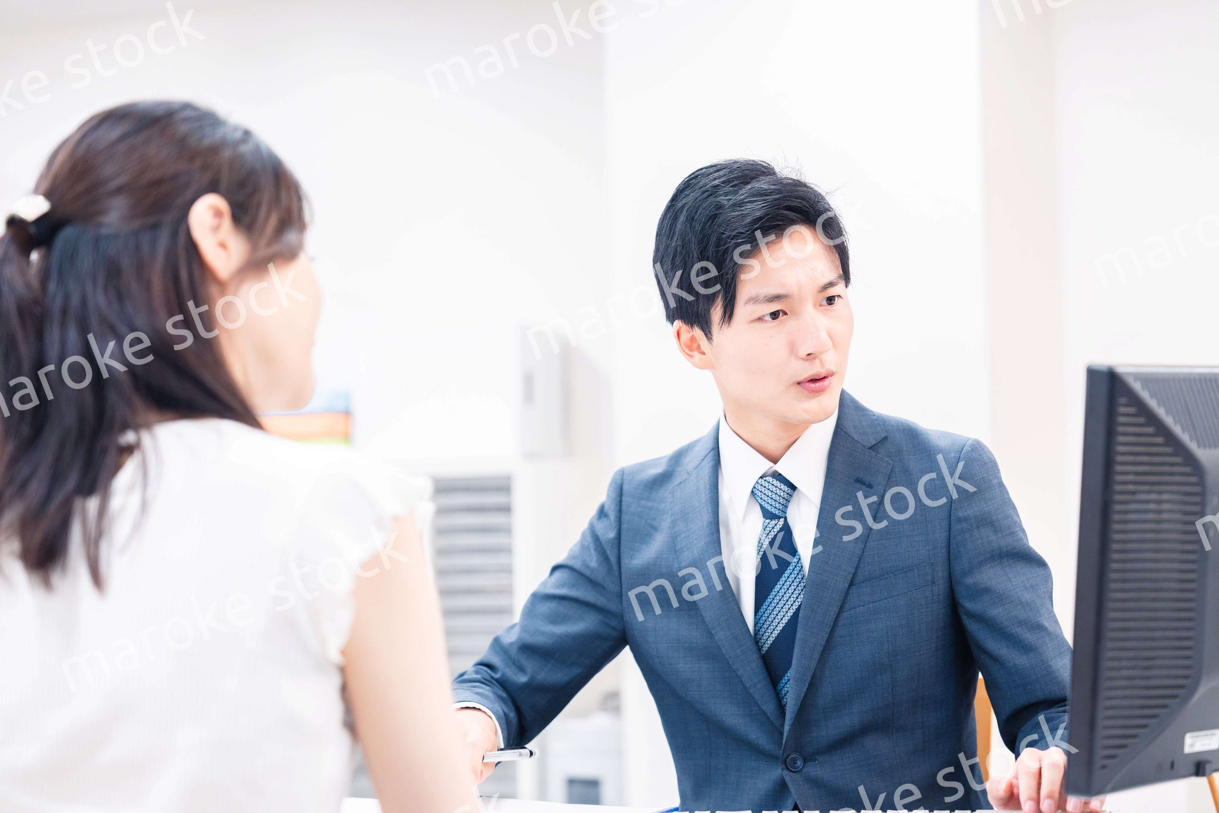 不動産会社のカウンターで相談をする若い女性