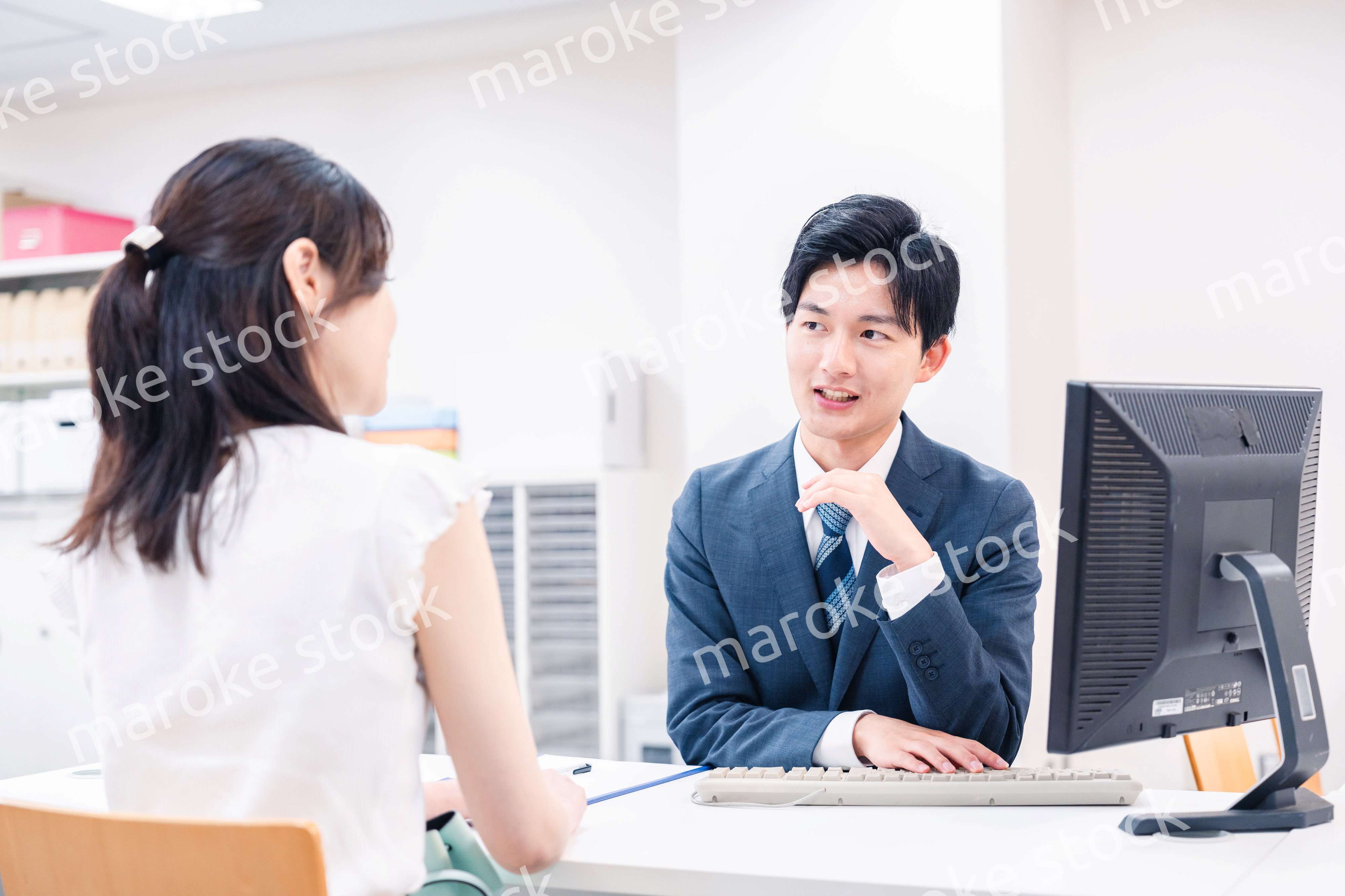 不動産会社のカウンターで相談をする若い女性