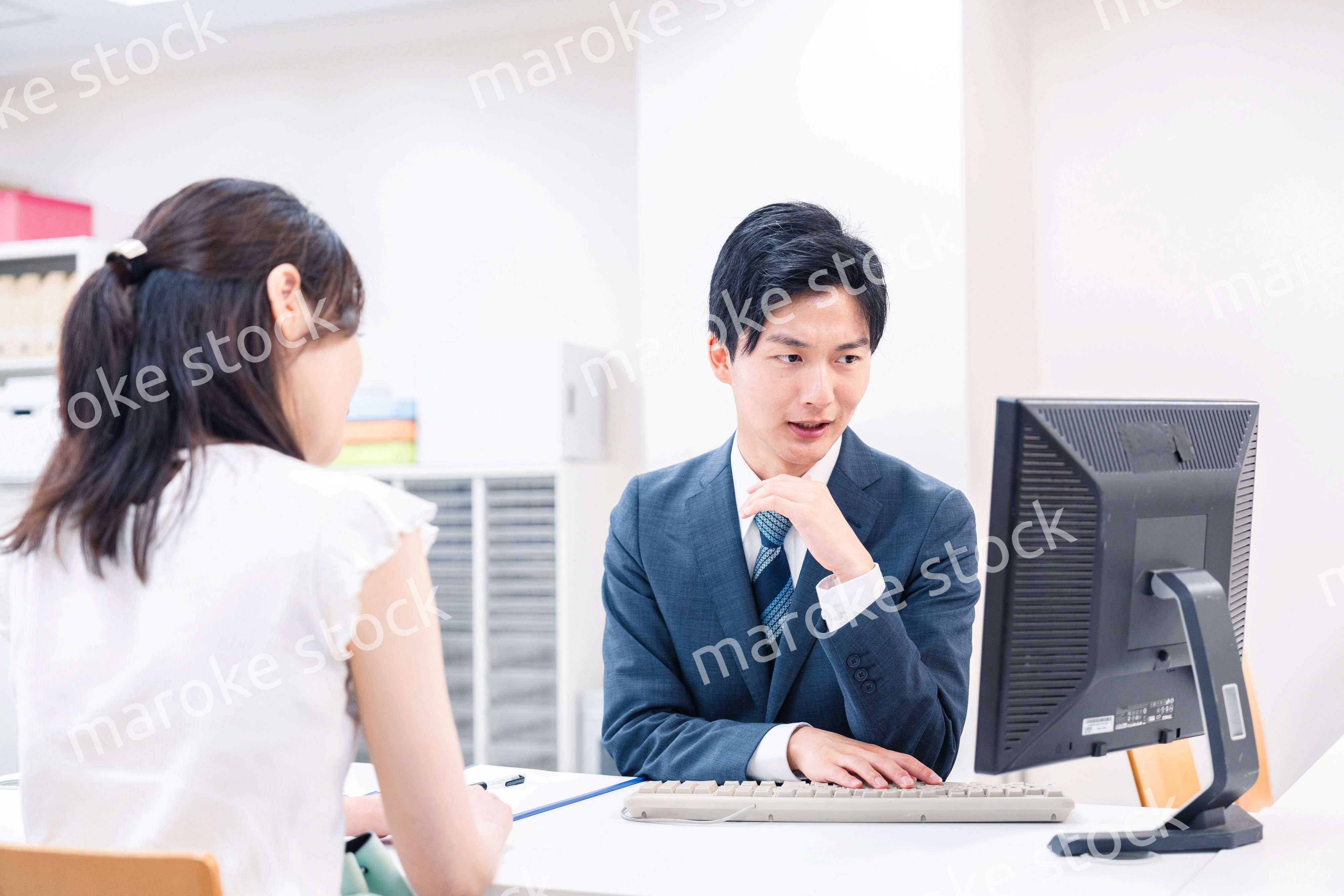 不動産会社のカウンターで相談をする若い女性