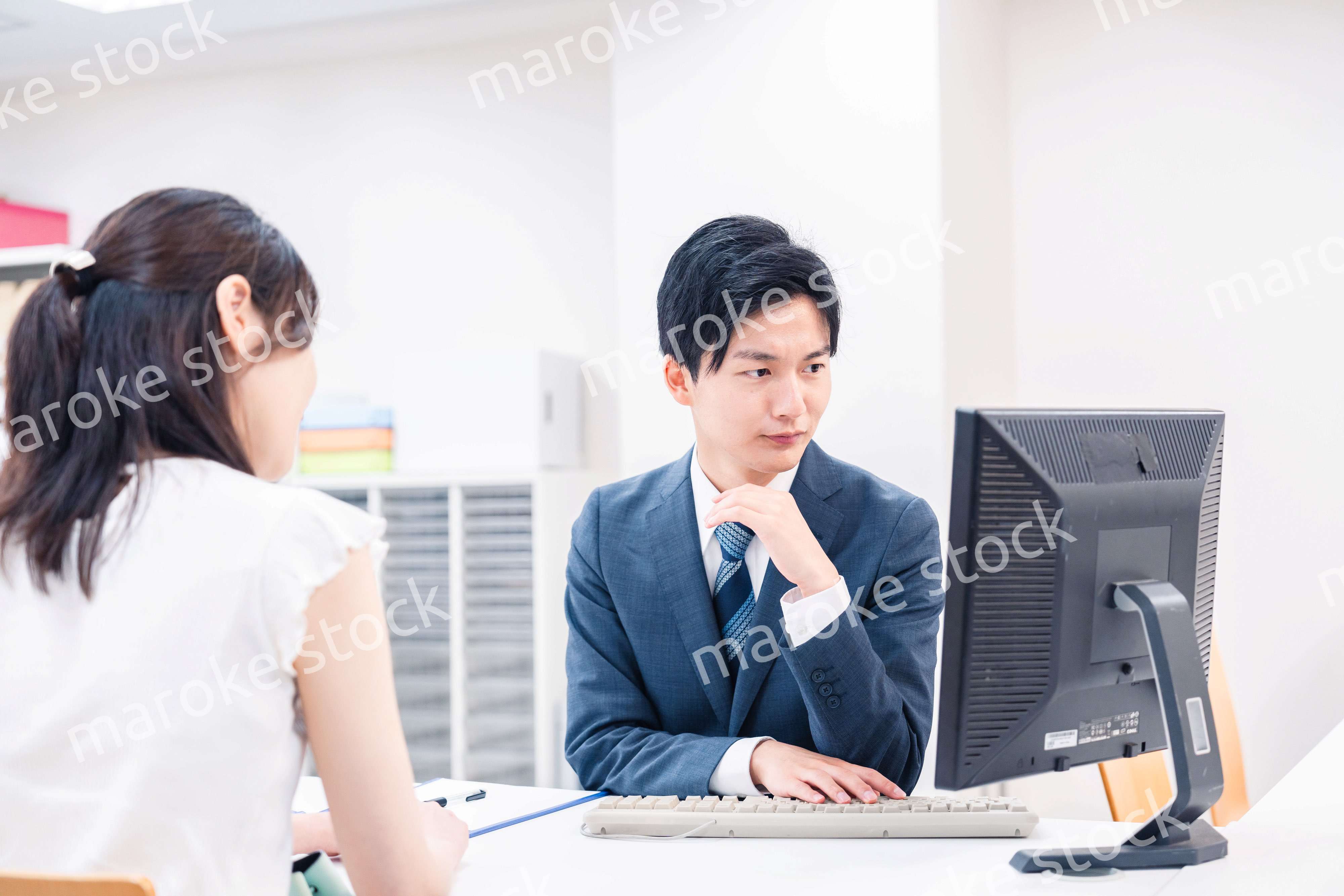 不動産会社のカウンターで相談をする若い女性