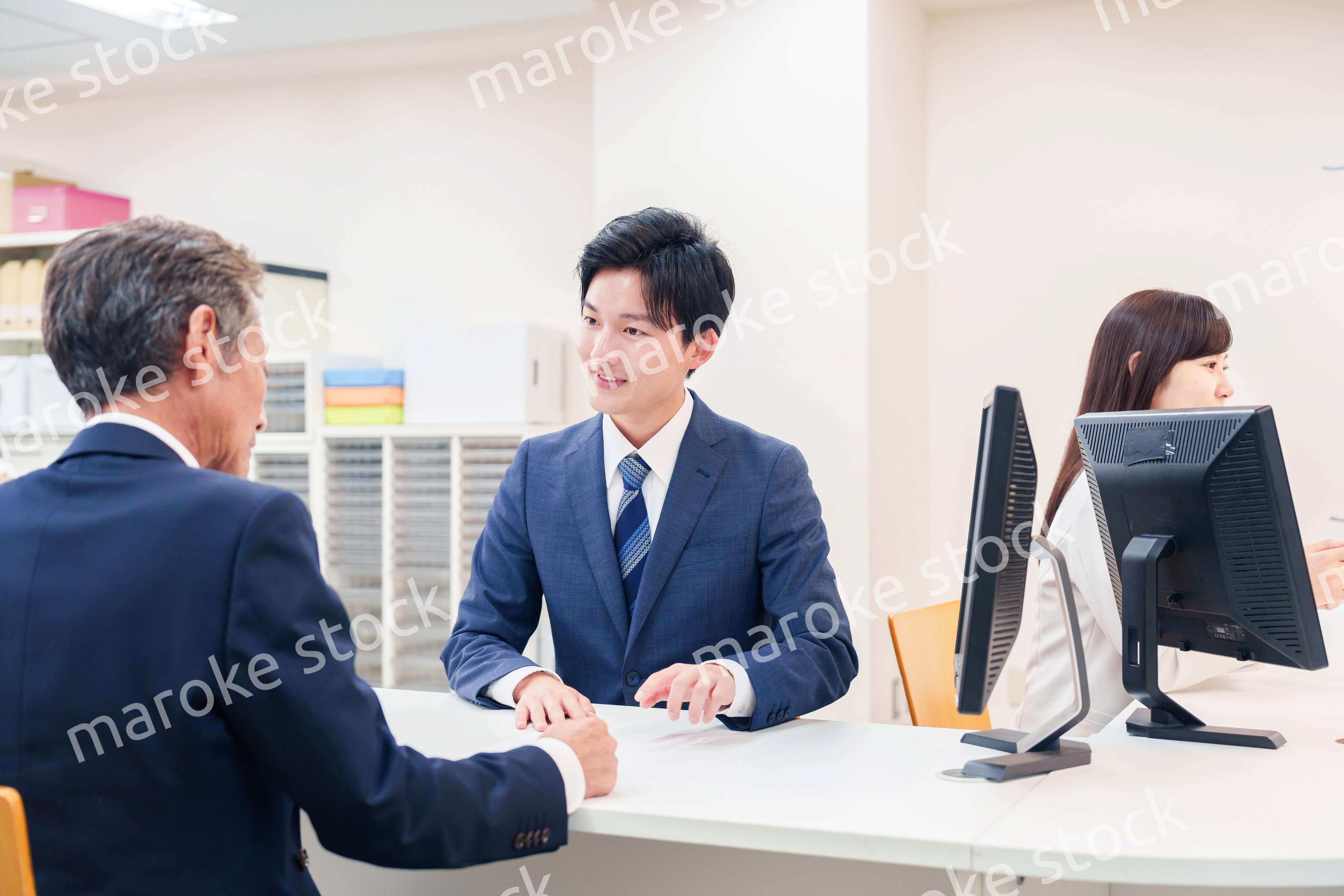 窓口で高齢者の来客の対応をする男性