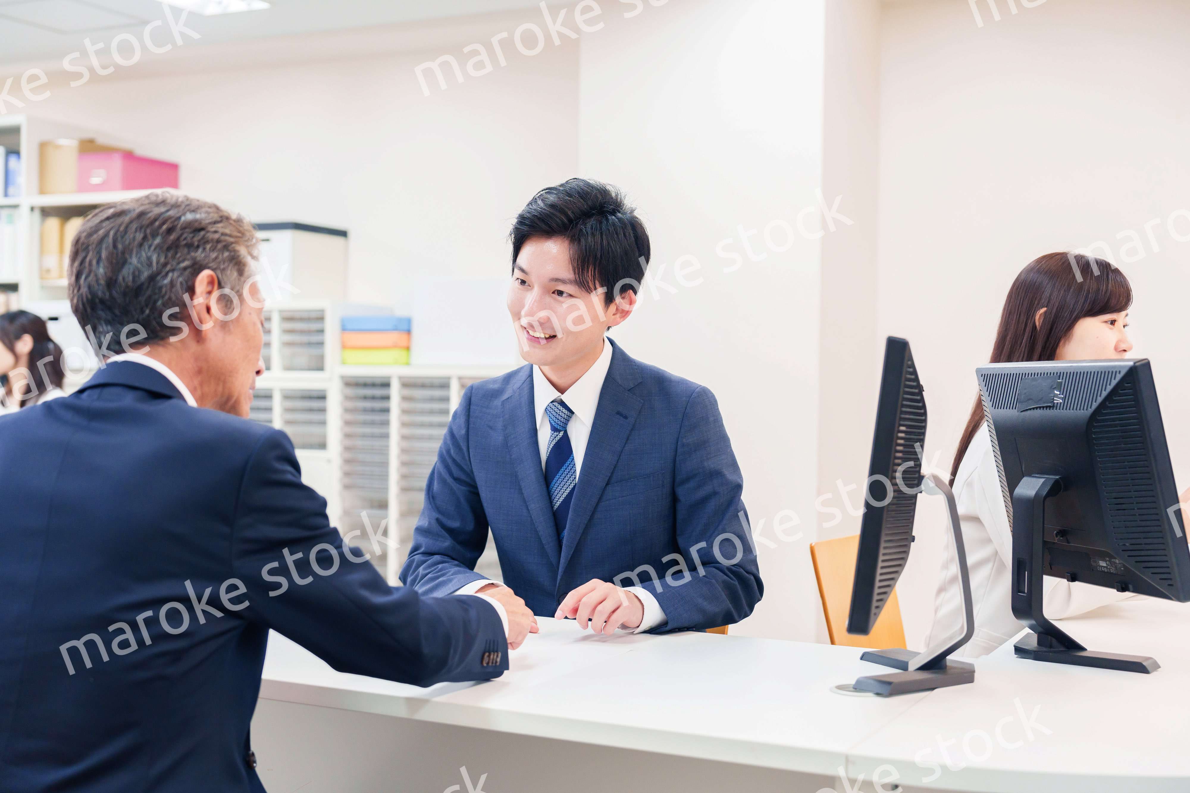 窓口で高齢者の来客の対応をする男性