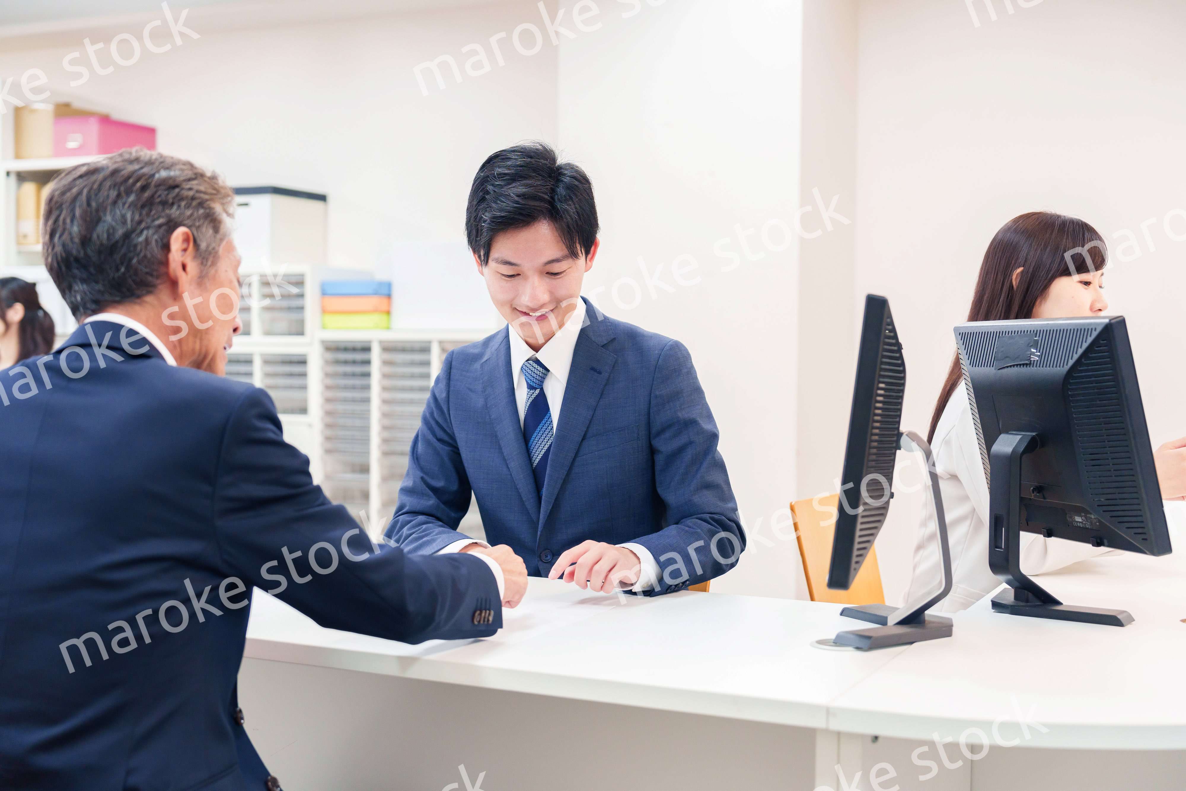 窓口で高齢者の来客の対応をする男性