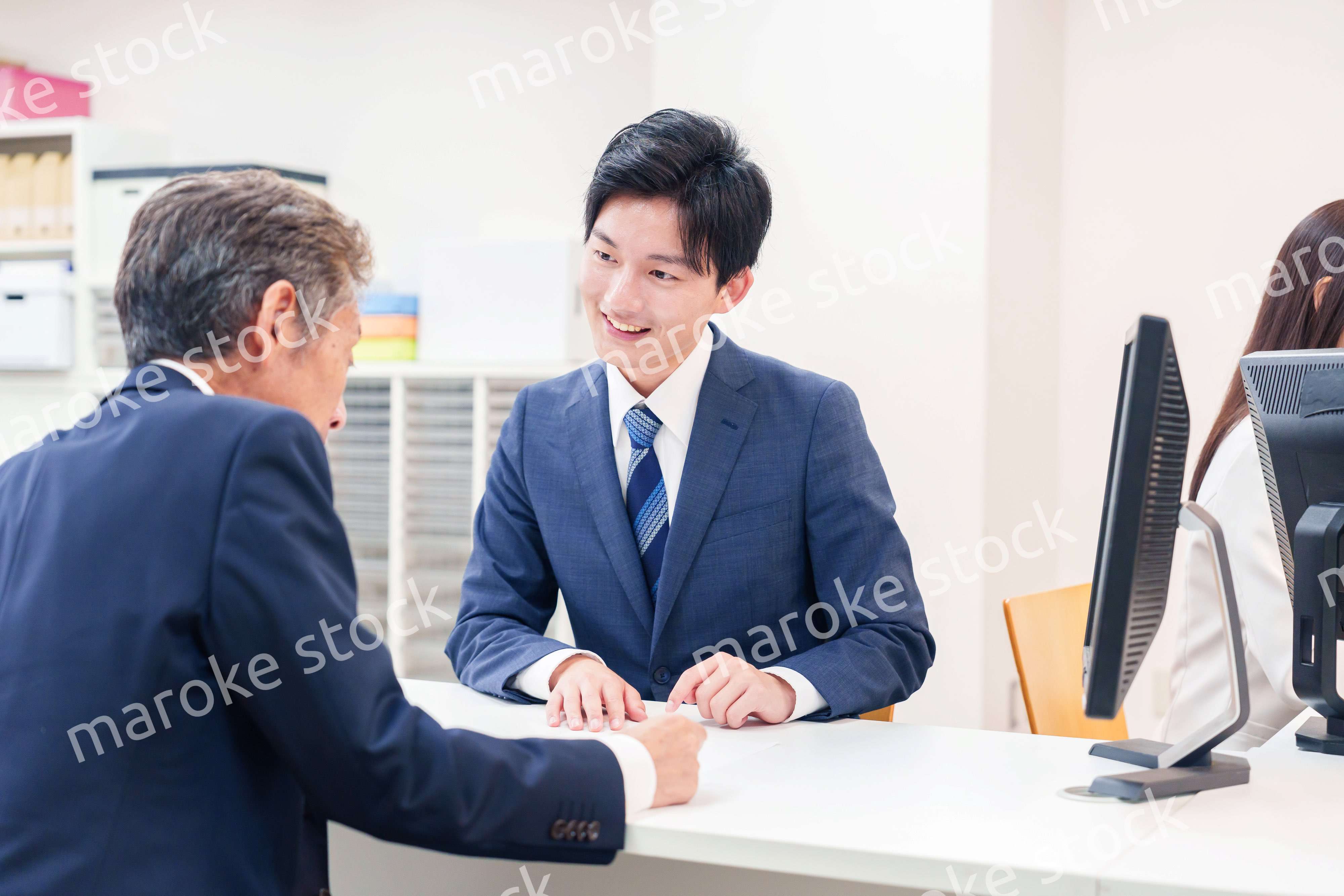 窓口で高齢者の来客の対応をする男性