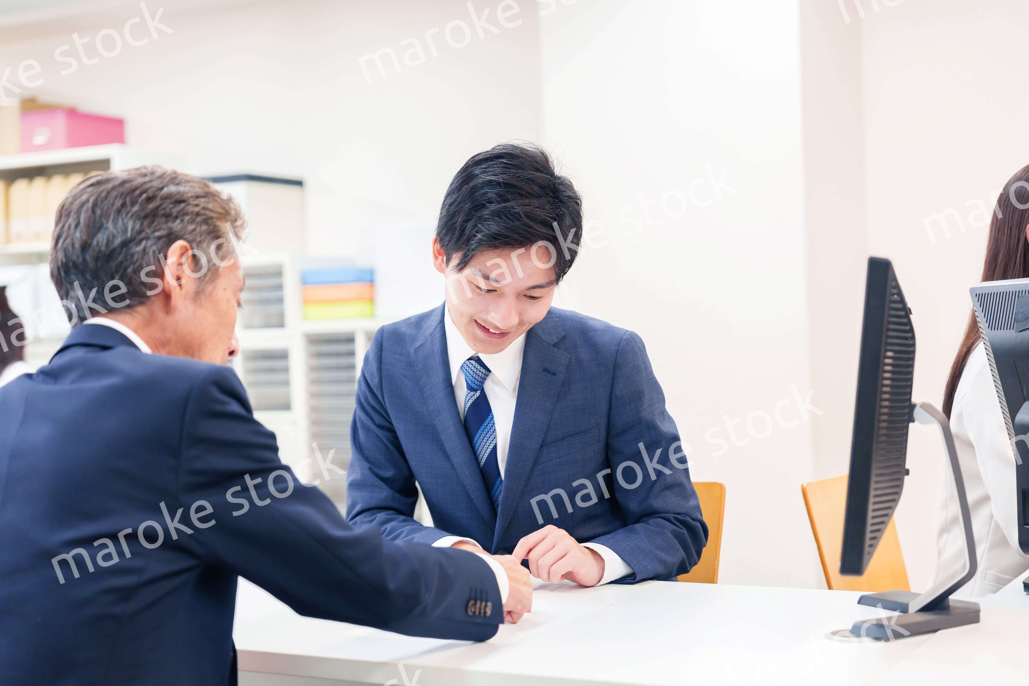 窓口で高齢者の来客の対応をする男性