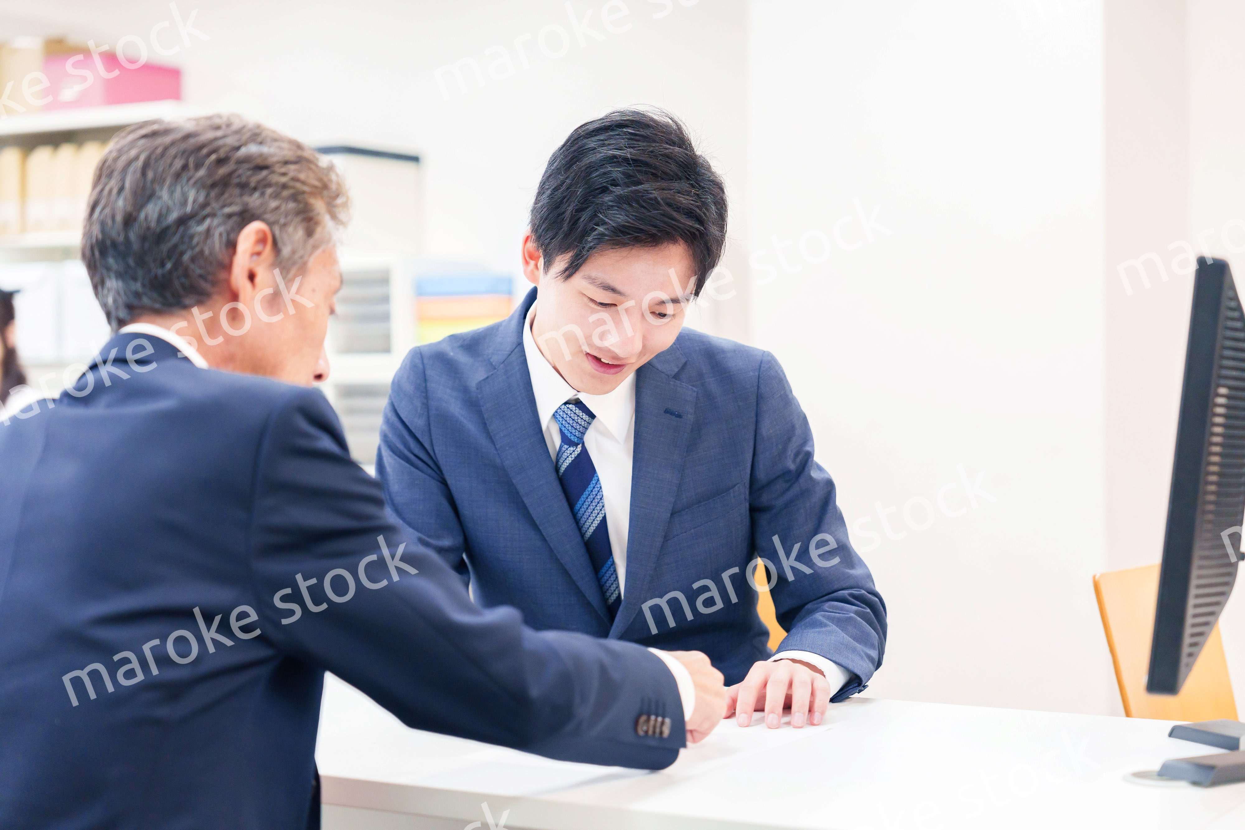 窓口で高齢者の来客の対応をする男性