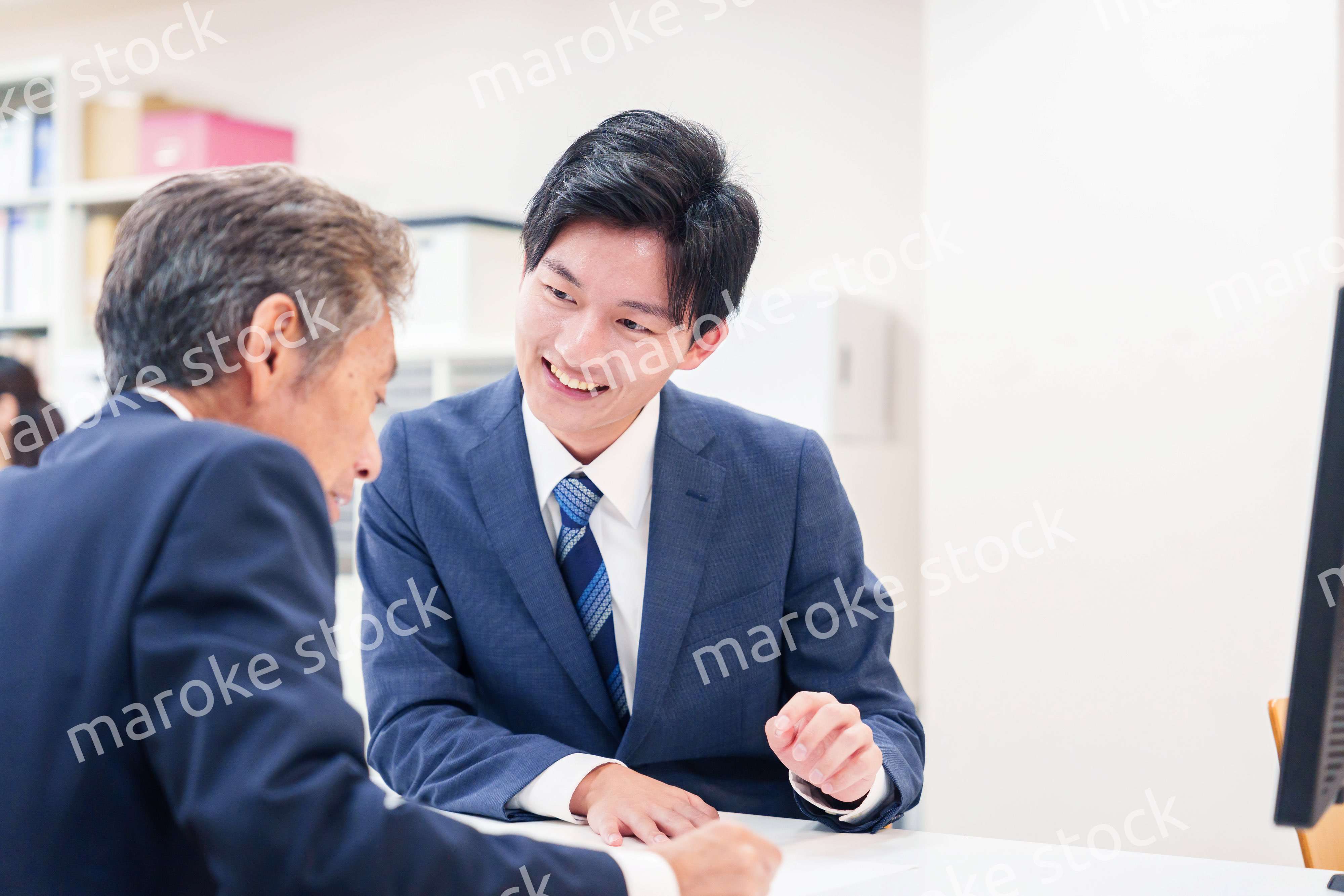 窓口で高齢者の来客の対応をする男性