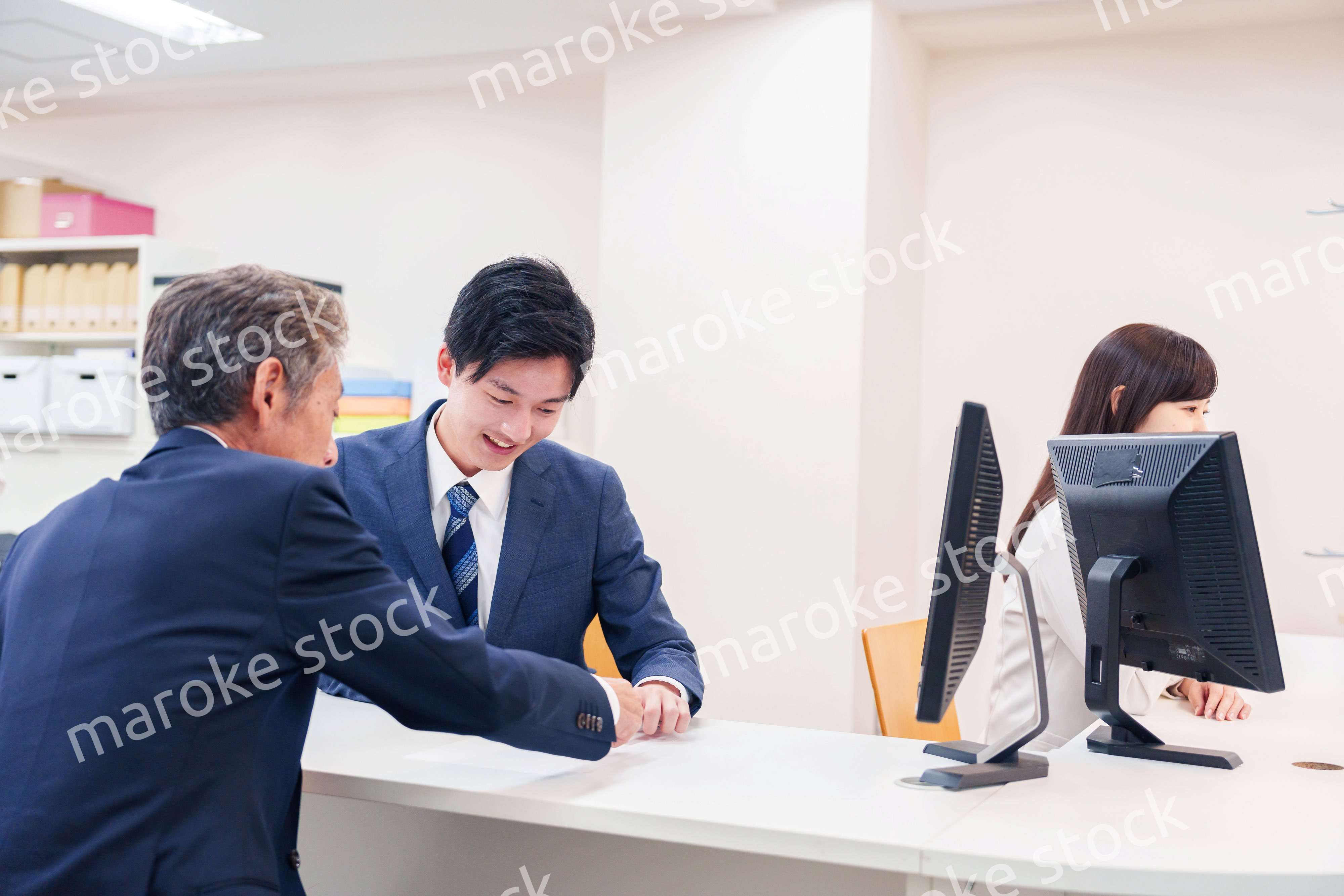 窓口で高齢者の来客の対応をする男性