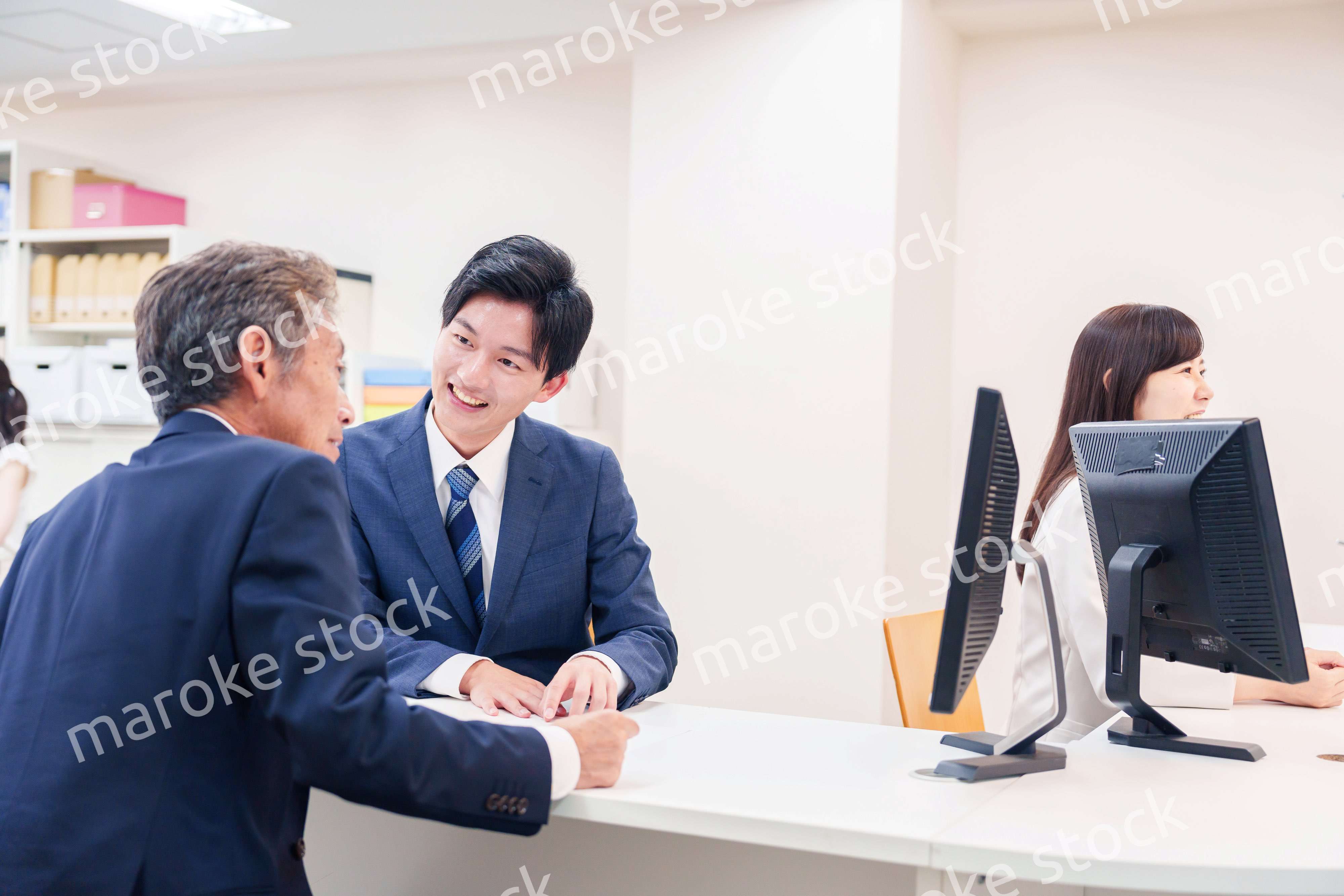 窓口で高齢者の来客の対応をする男性