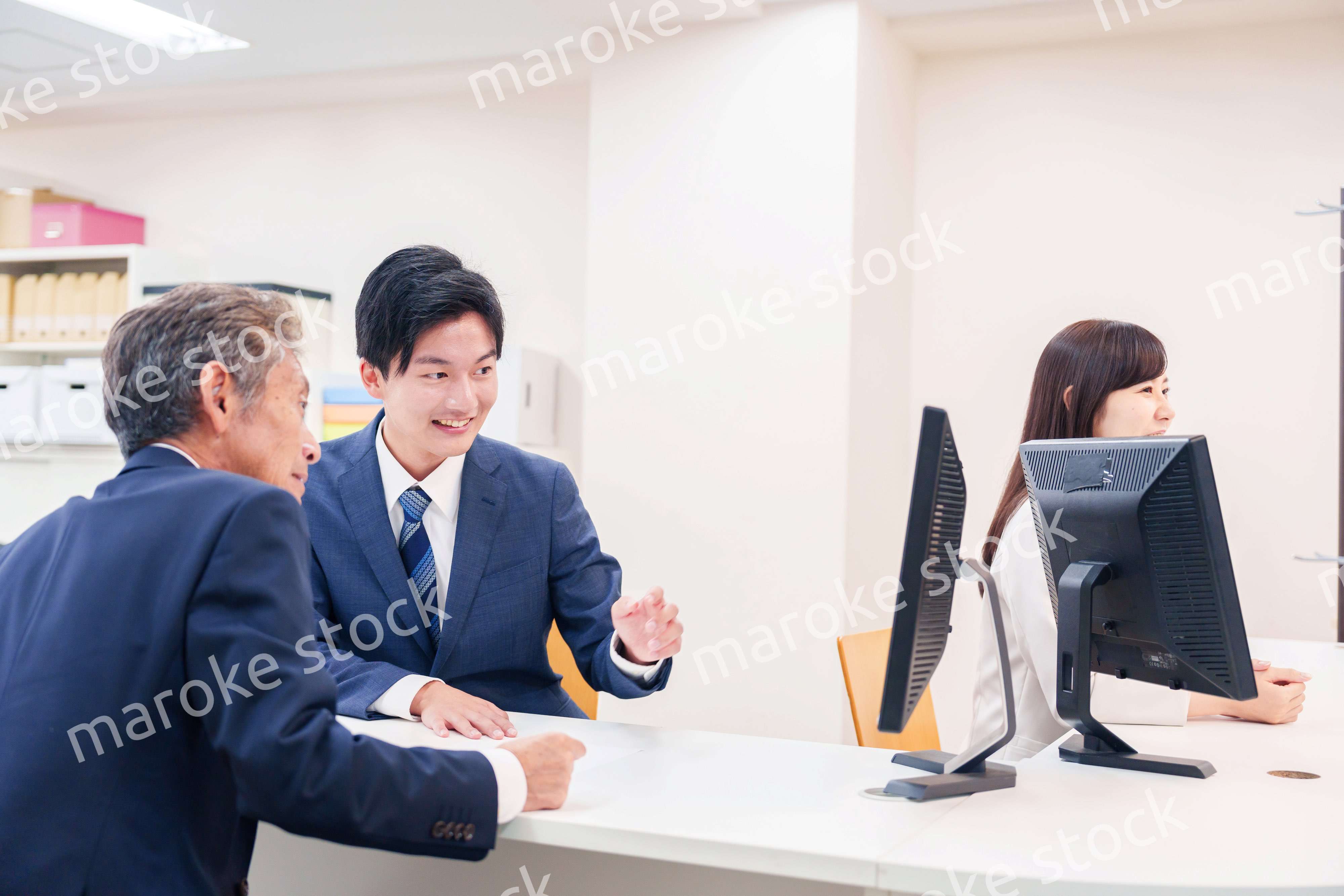 窓口で高齢者の来客の対応をする男性