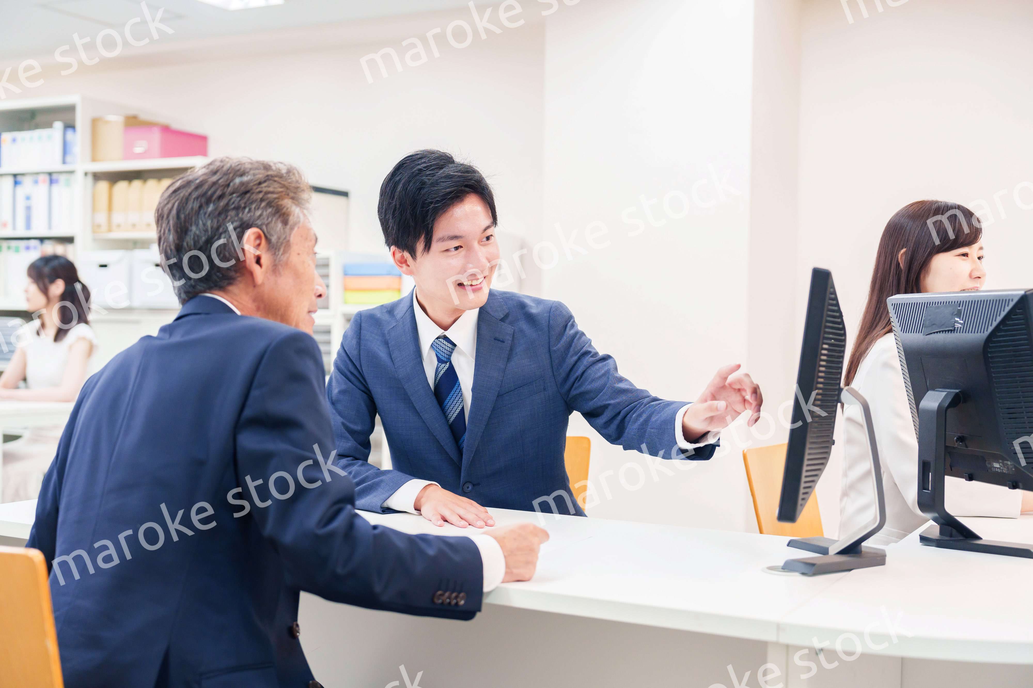 窓口で高齢者の来客の対応をする男性