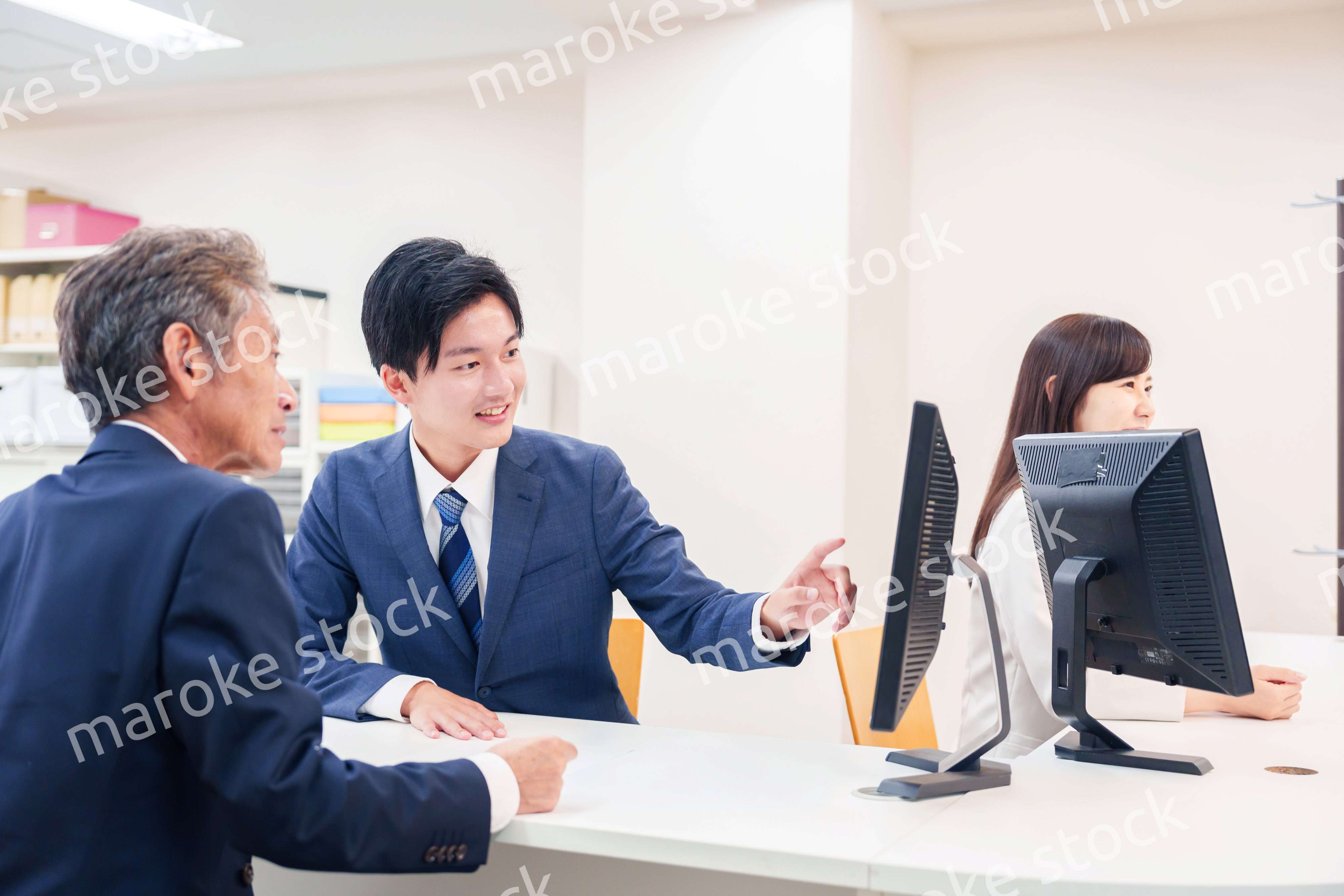 窓口で高齢者の来客の対応をする男性