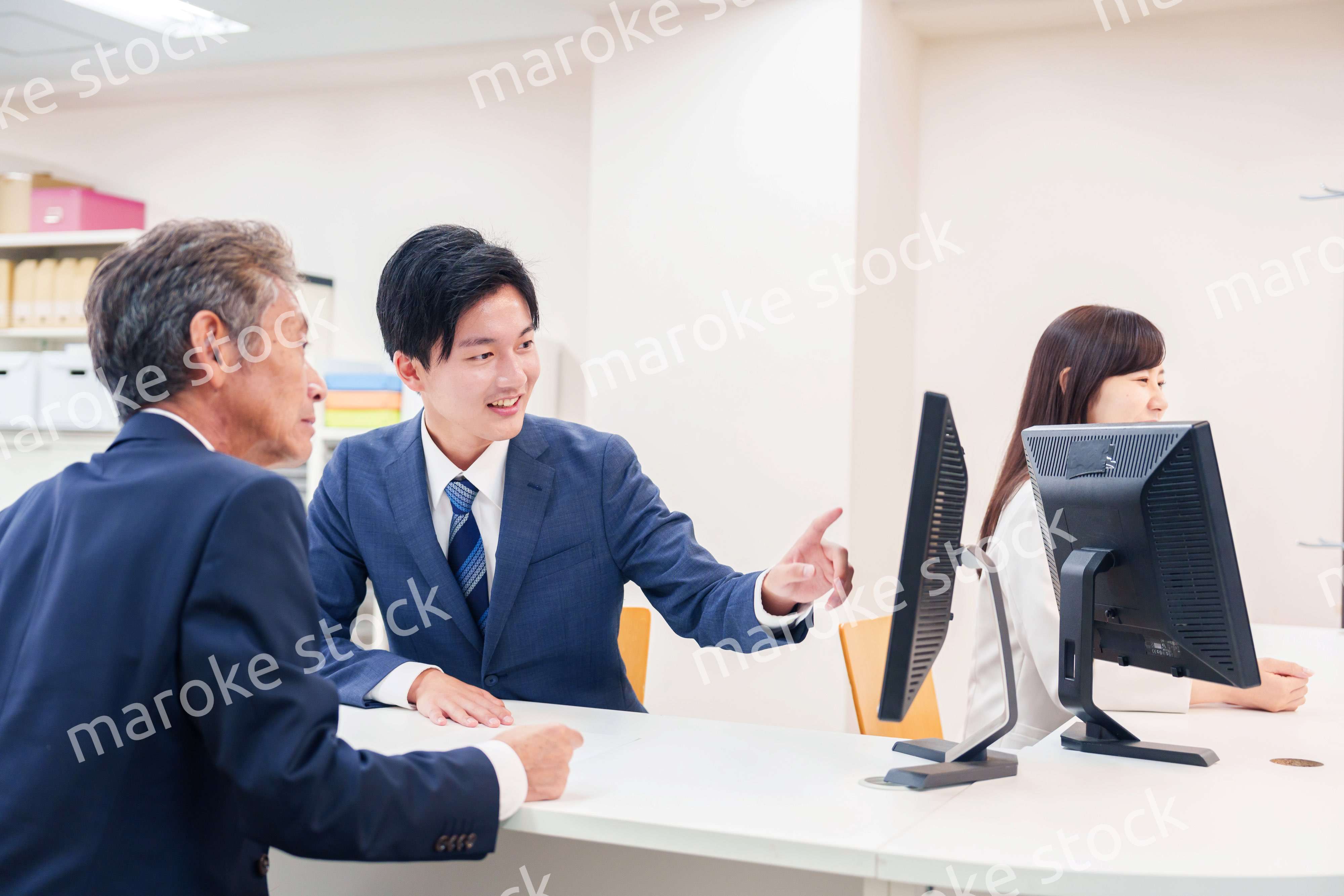 窓口で高齢者の来客の対応をする男性