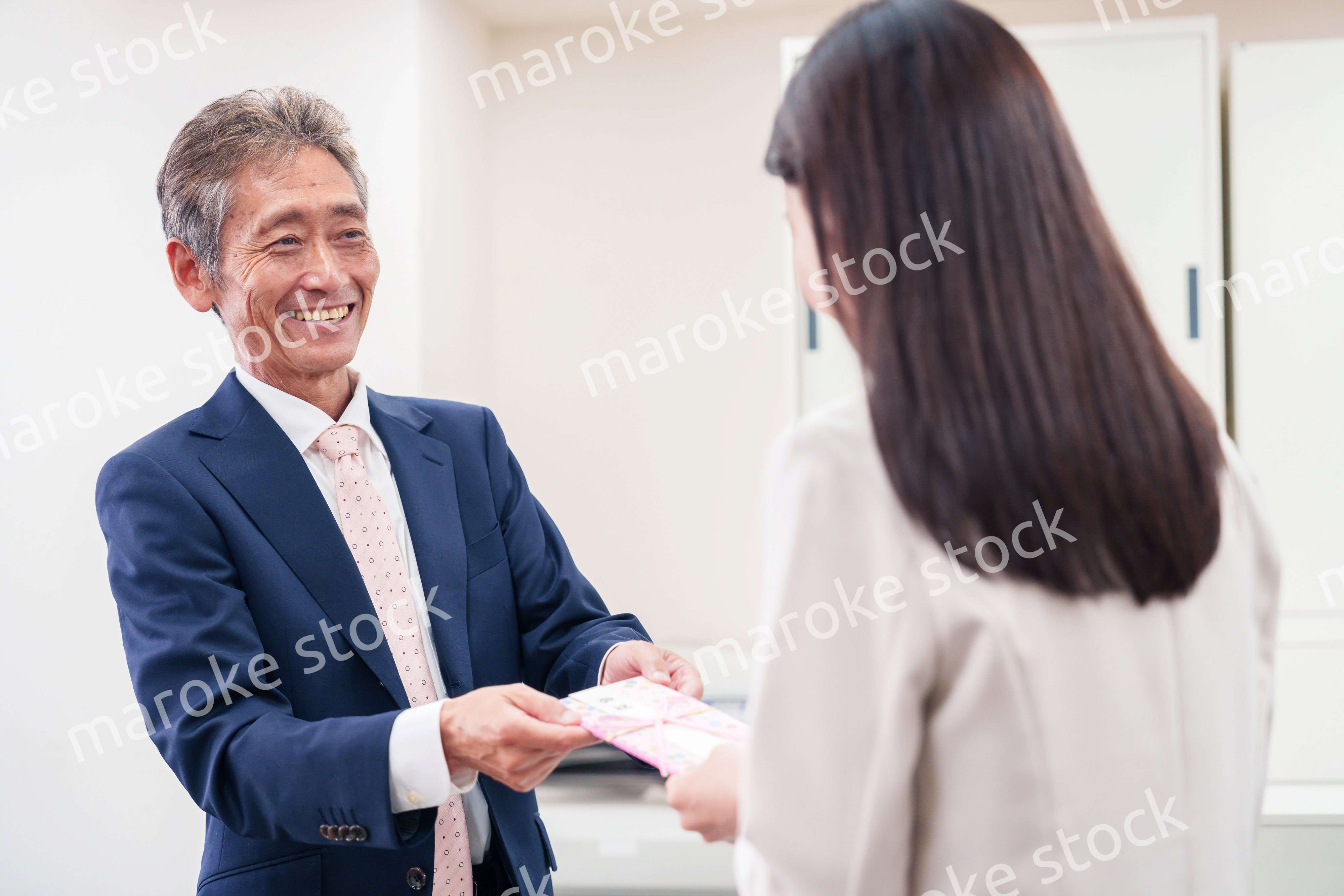 上司からお祝いを手渡されるビジネスウーマン