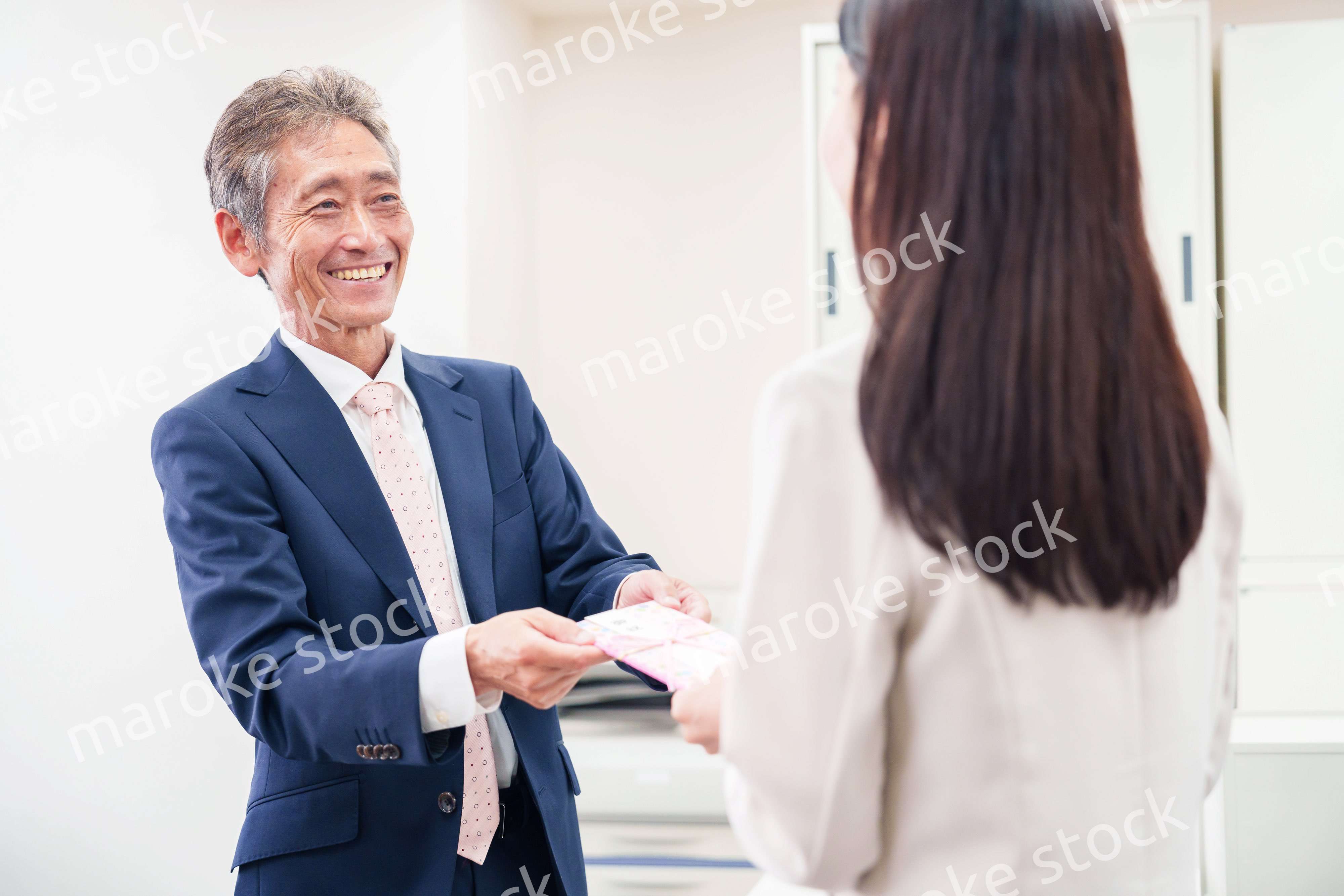 上司からお祝いを手渡されるビジネスウーマン