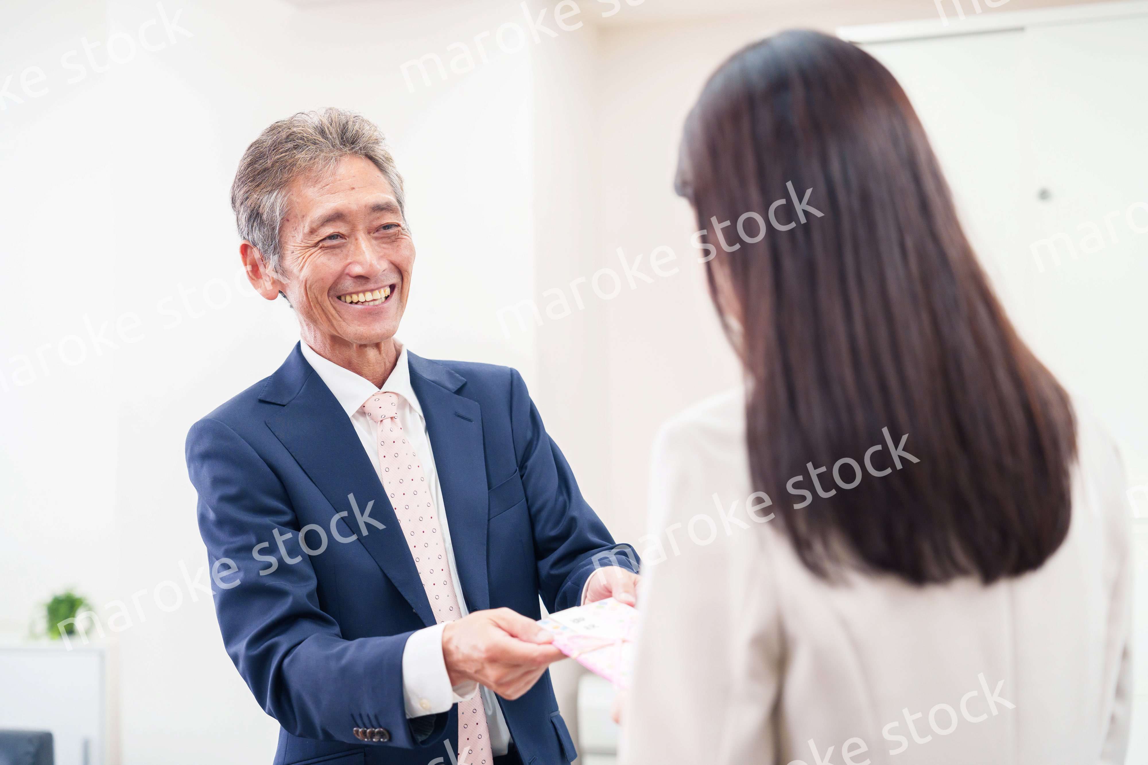 上司からお祝いを手渡されるビジネスウーマン