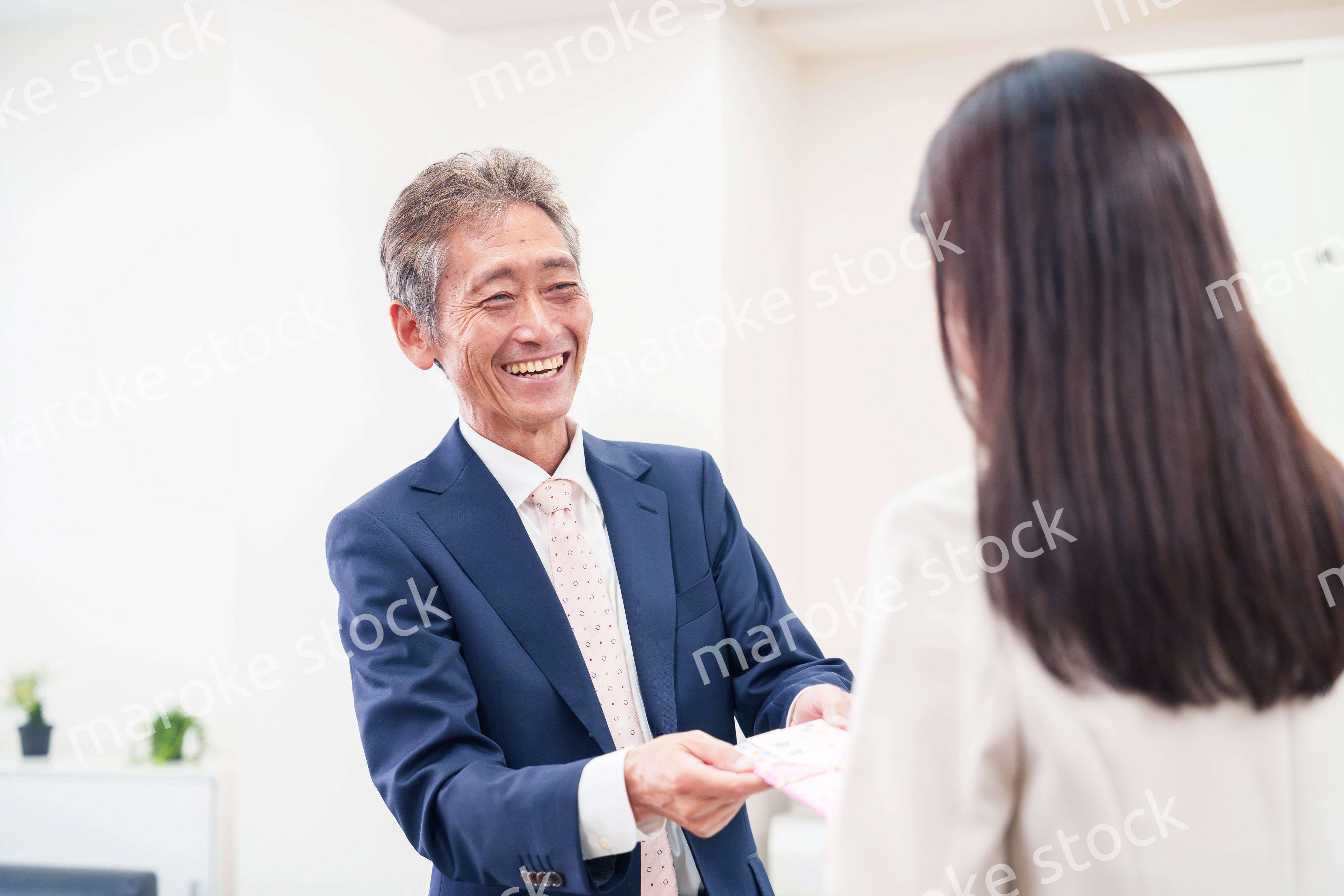 上司からお祝いを手渡されるビジネスウーマン