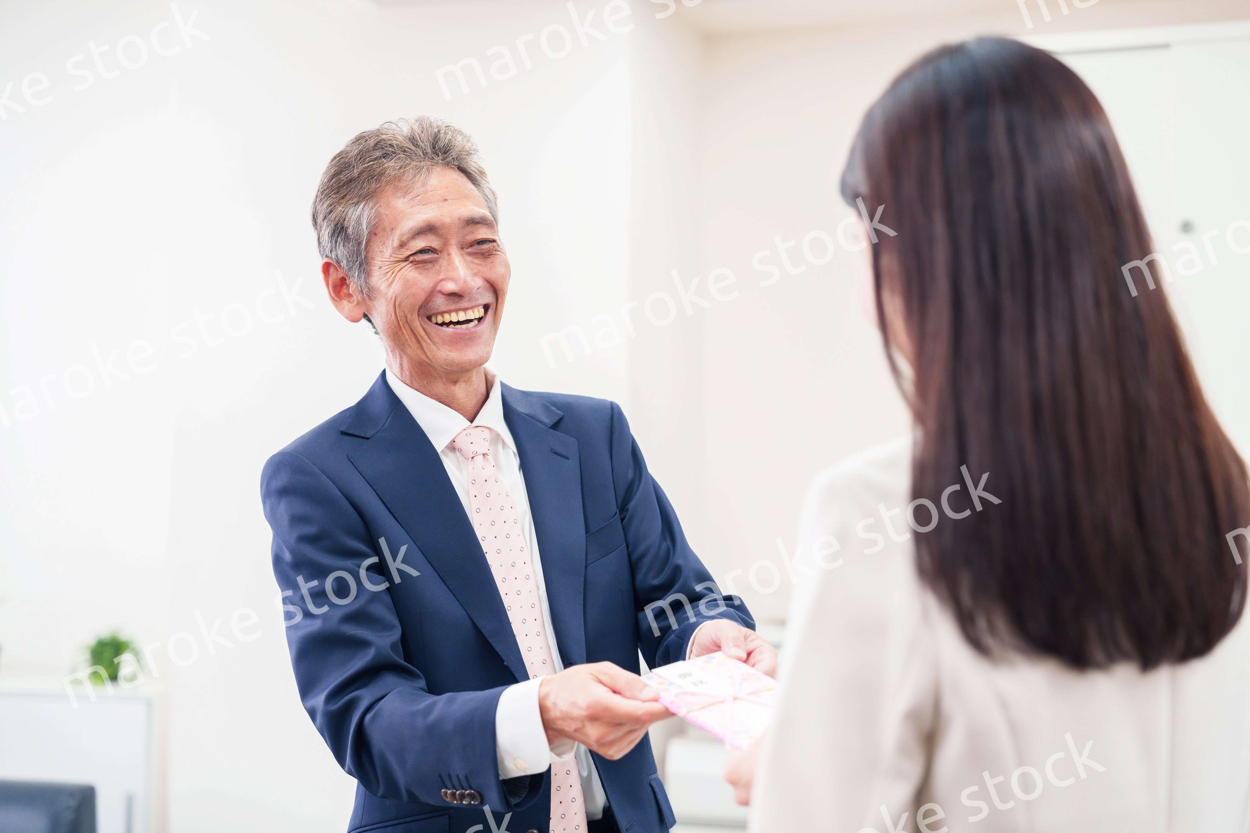 上司からお祝いを手渡されるビジネスウーマン