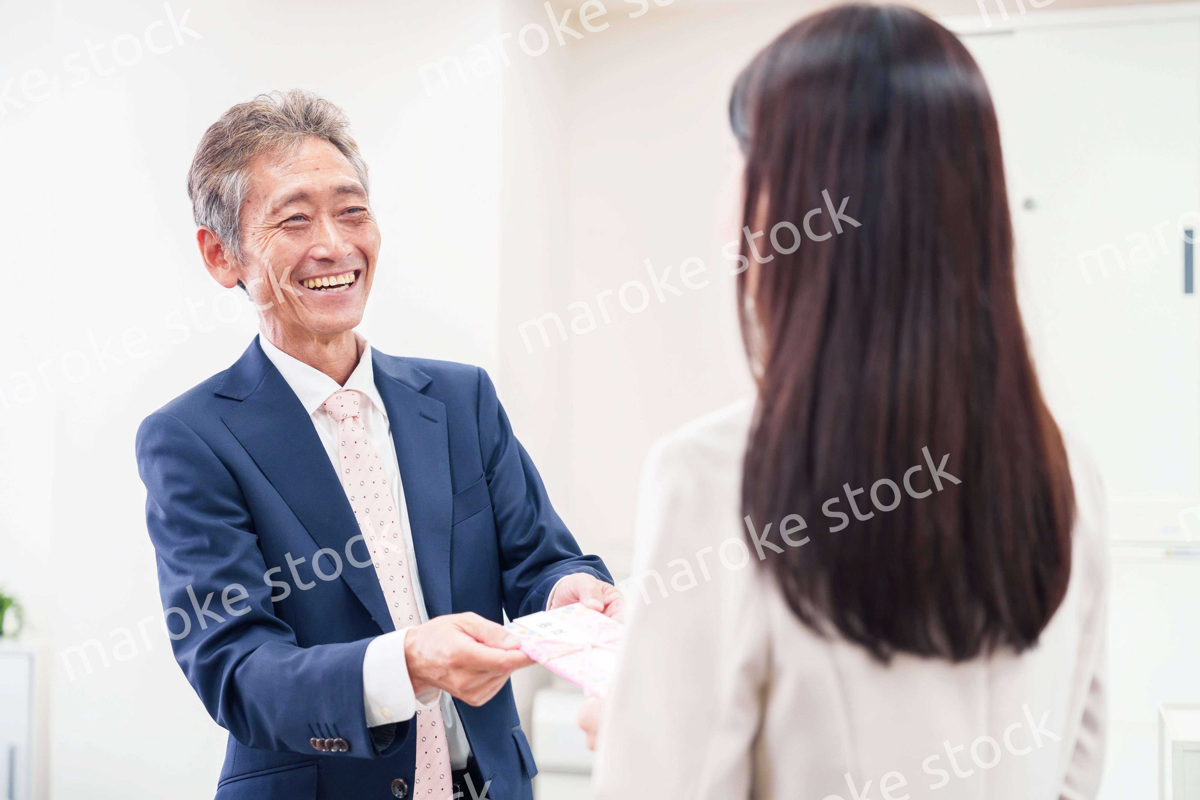 上司からお祝いを手渡されるビジネスウーマン