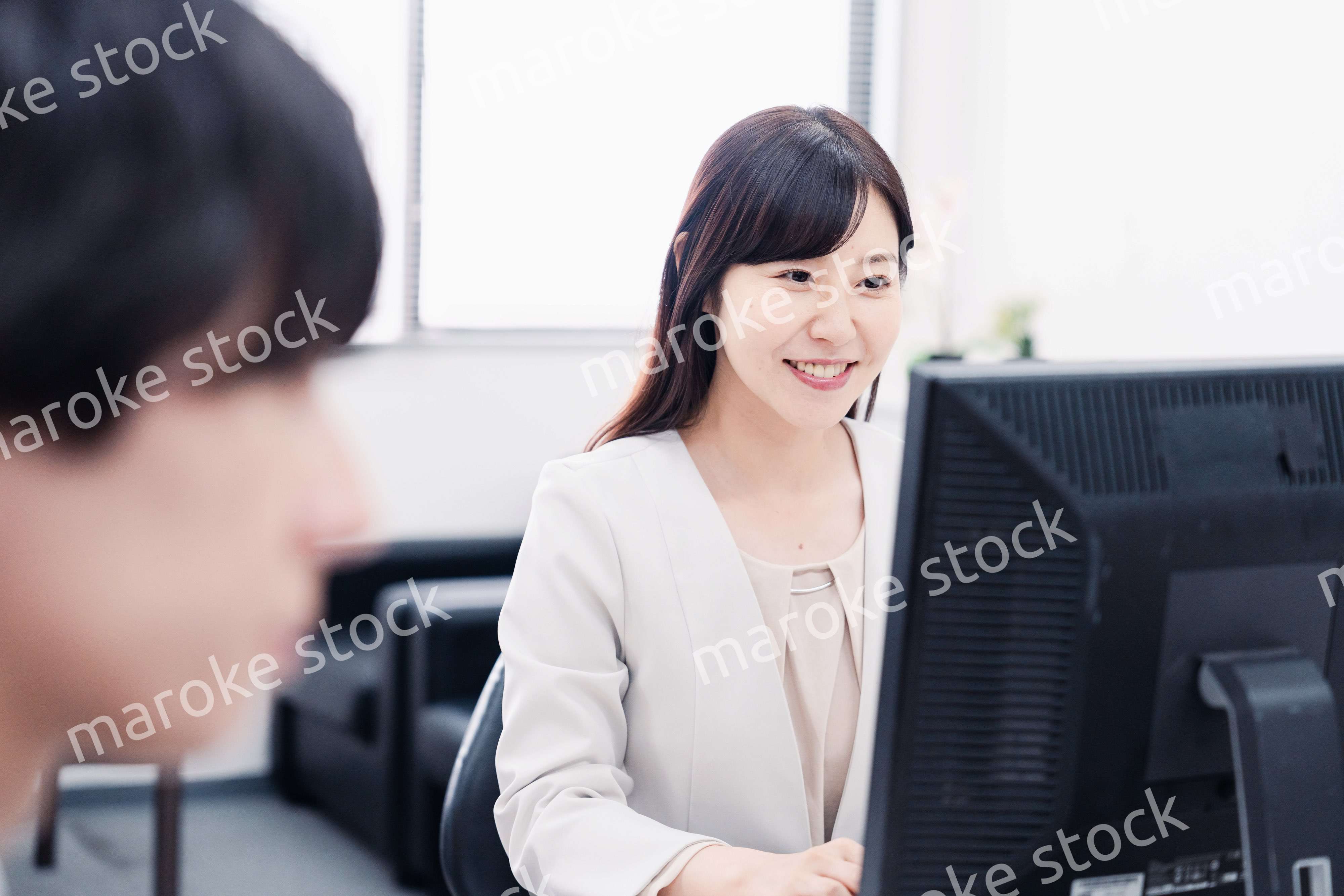 オフィスで笑顔で仕事をするオフィスワーカー