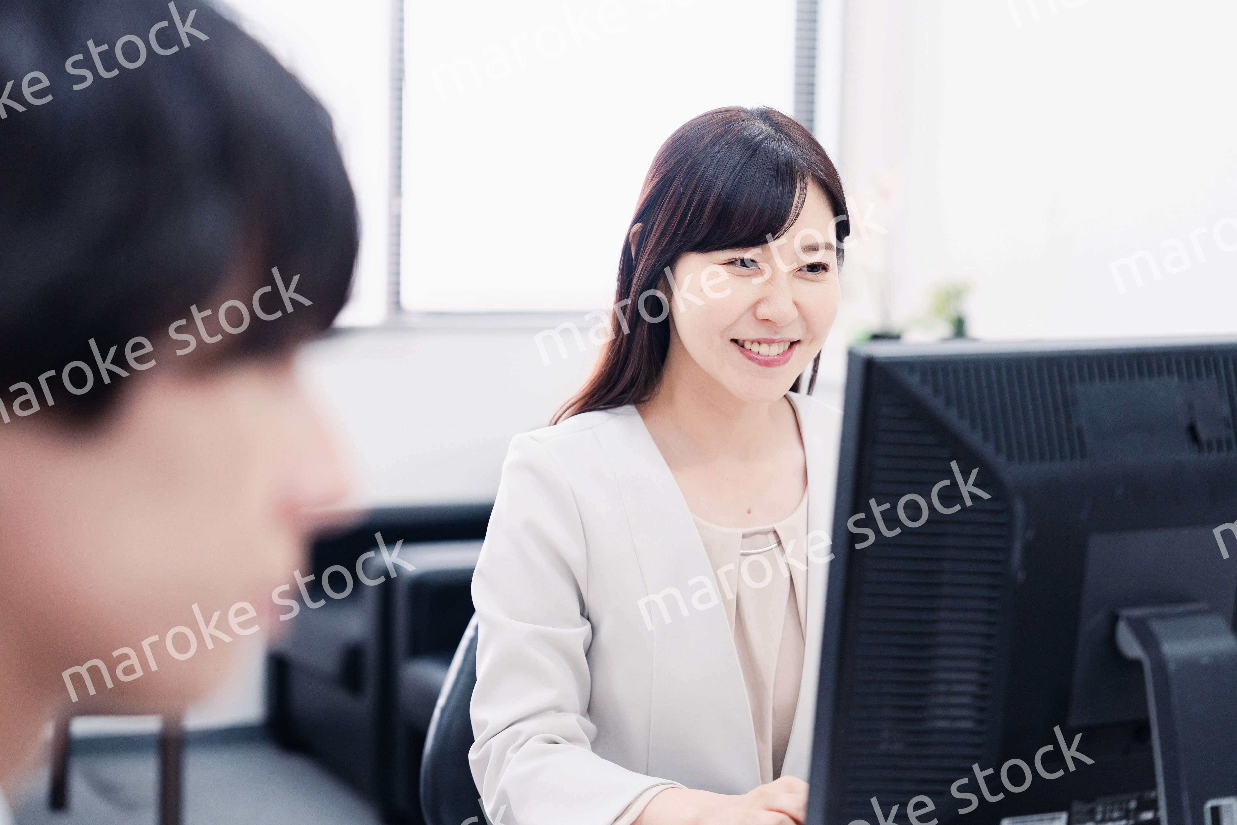 オフィスで笑顔で仕事をするオフィスワーカー