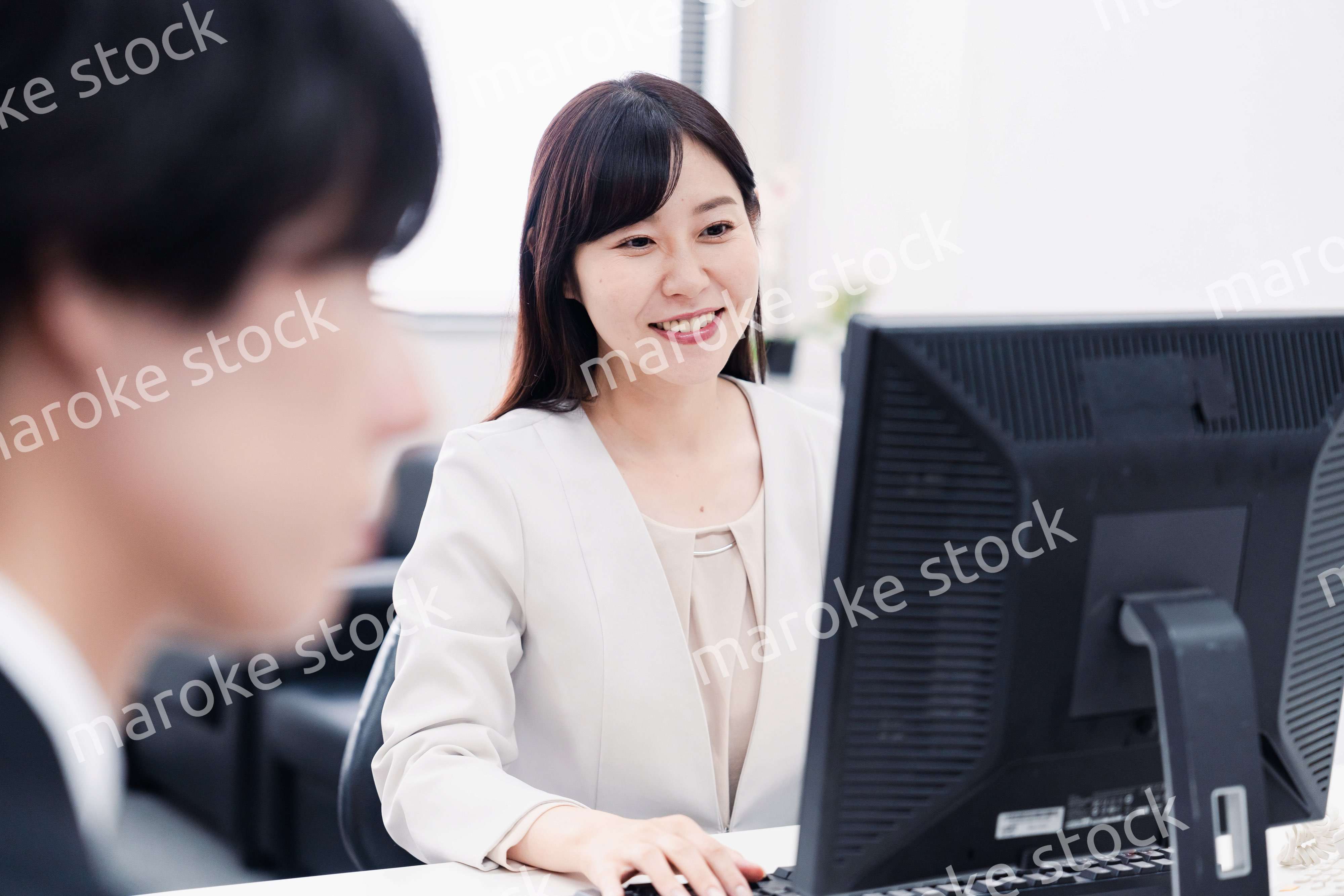 オフィスで笑顔で仕事をするオフィスワーカー