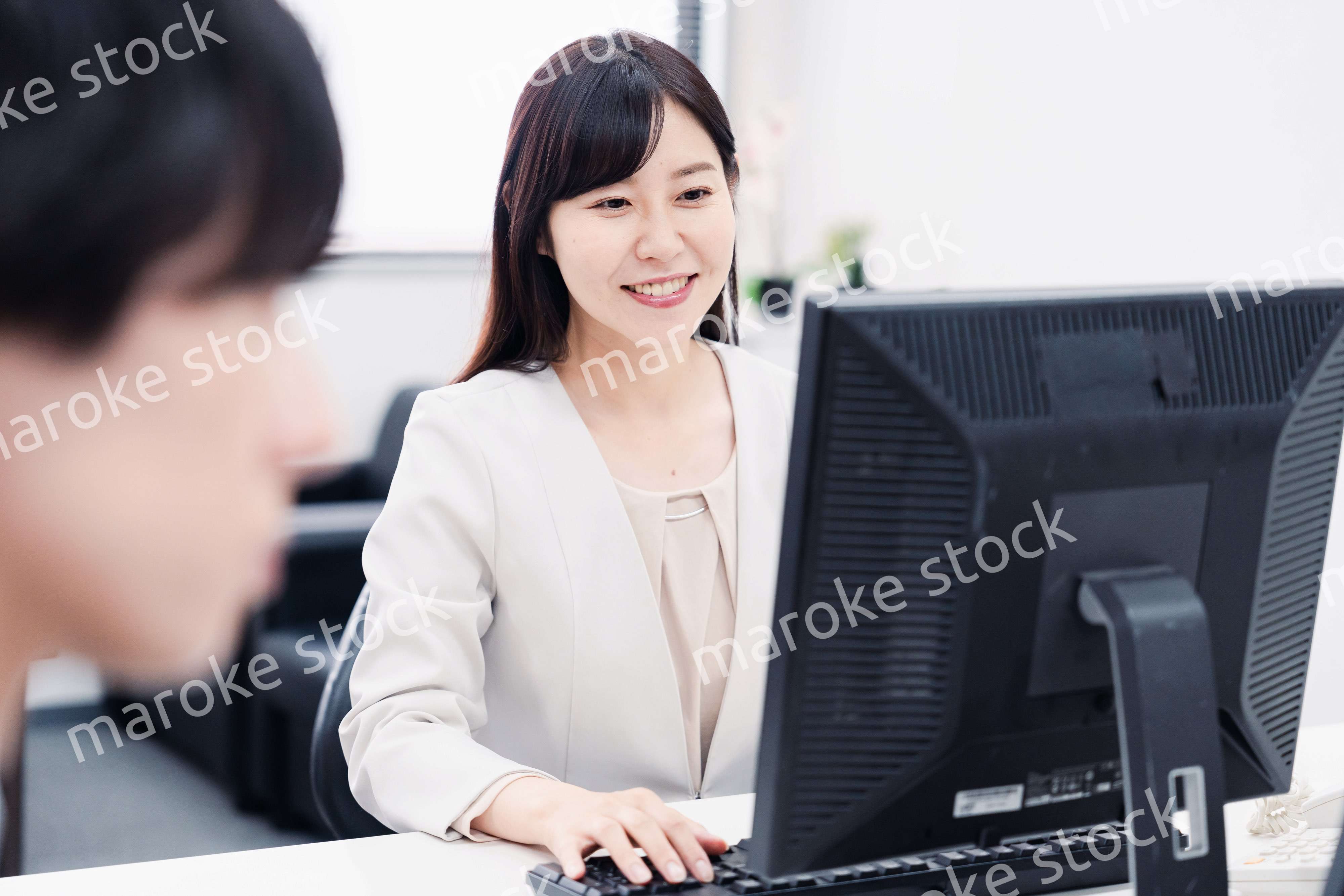 オフィスで笑顔で仕事をするオフィスワーカー