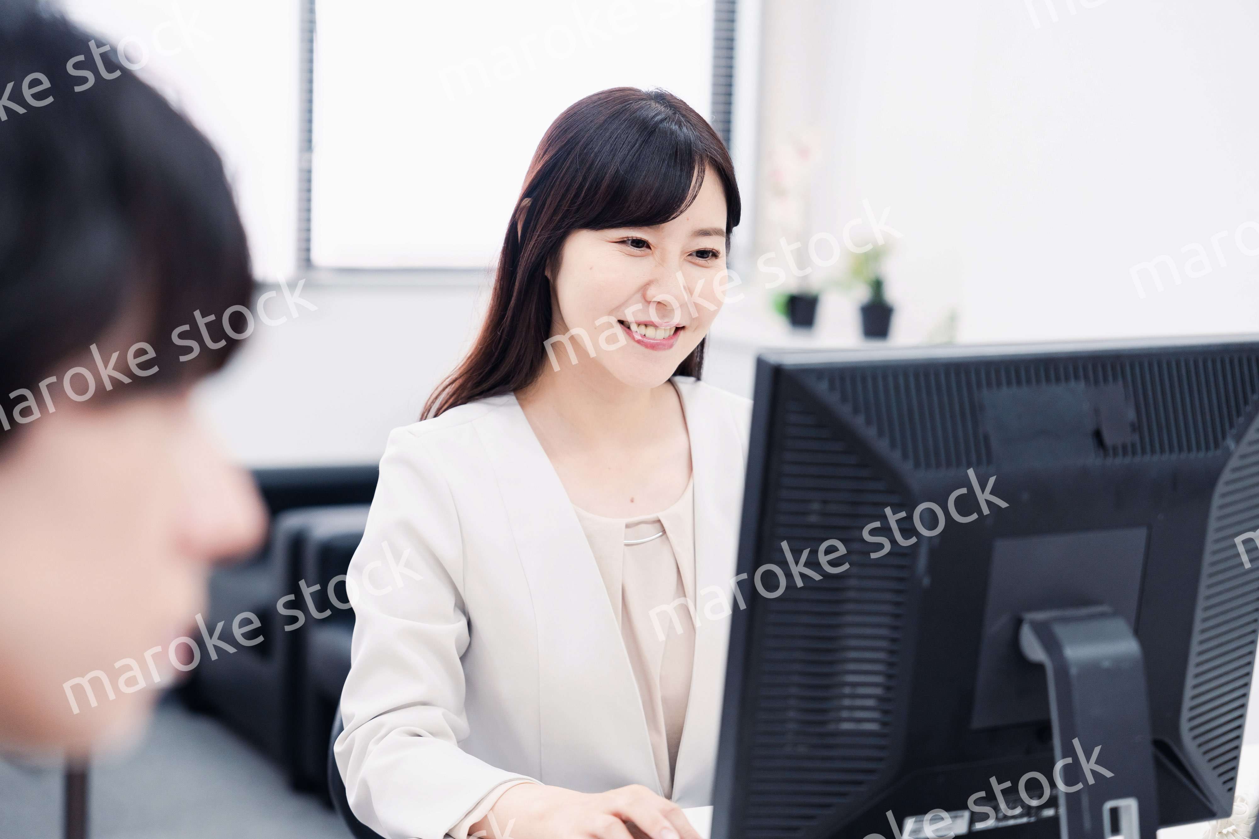 オフィスで笑顔で仕事をするオフィスワーカー