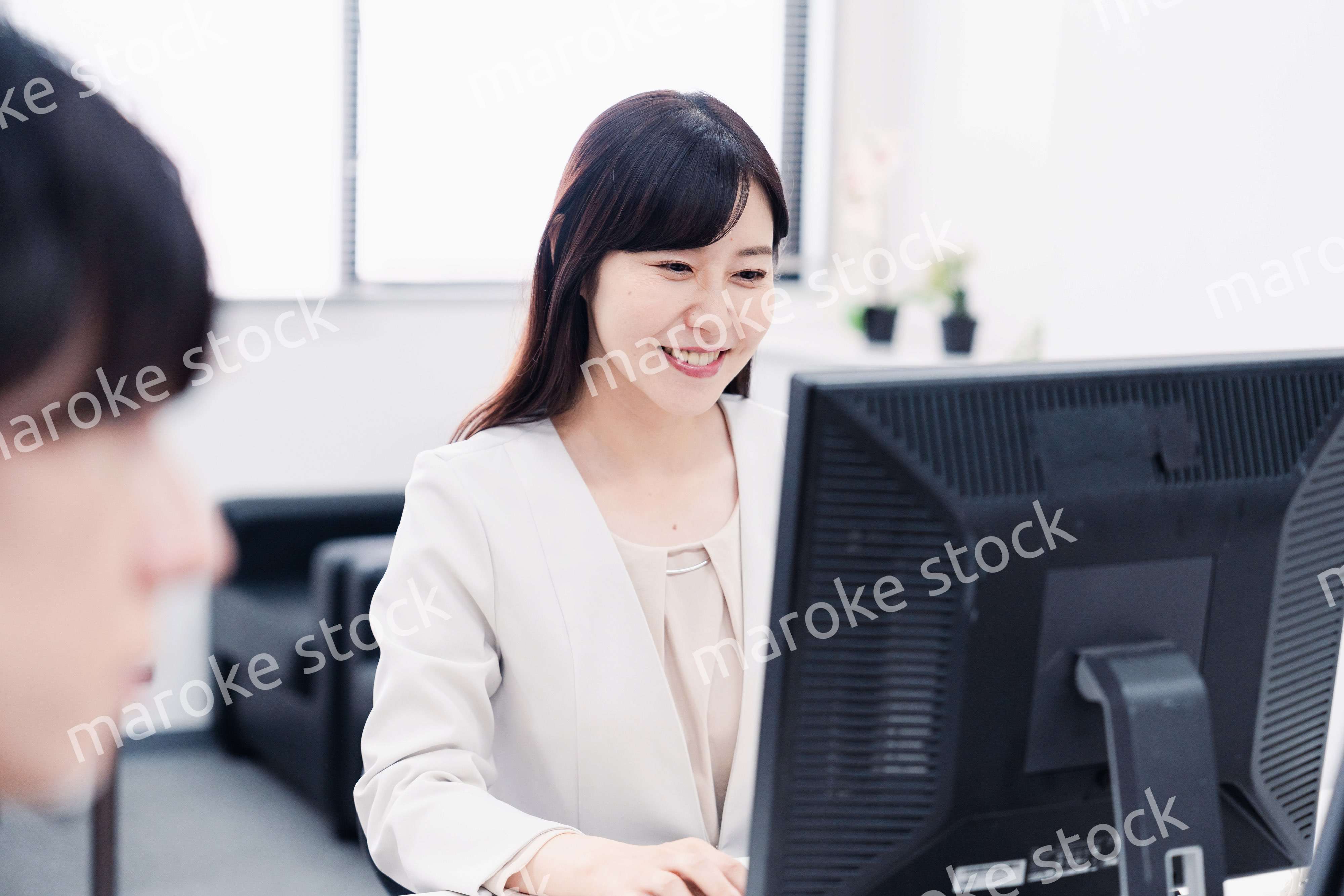 オフィスで笑顔で仕事をするオフィスワーカー