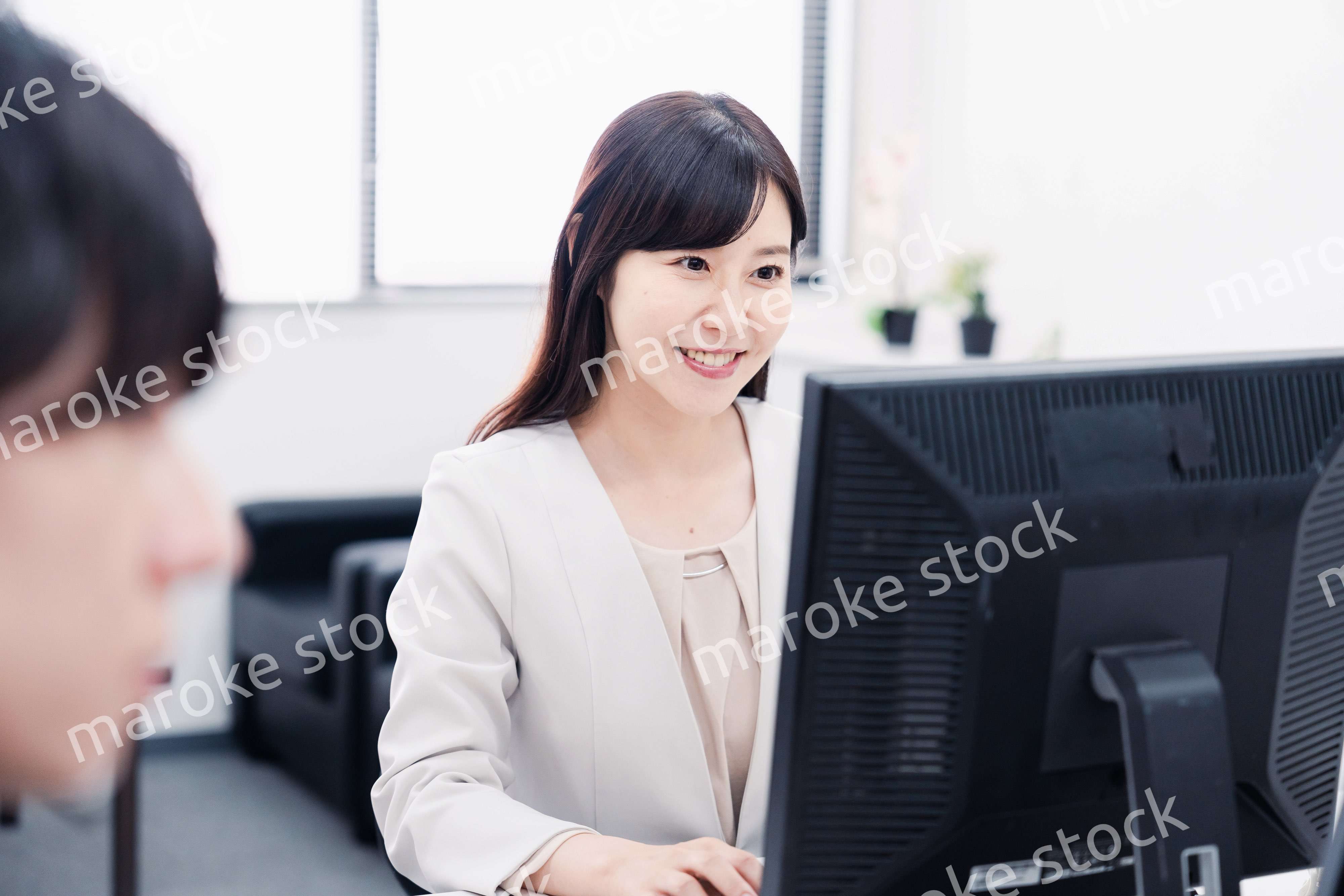 オフィスで笑顔で仕事をするオフィスワーカー