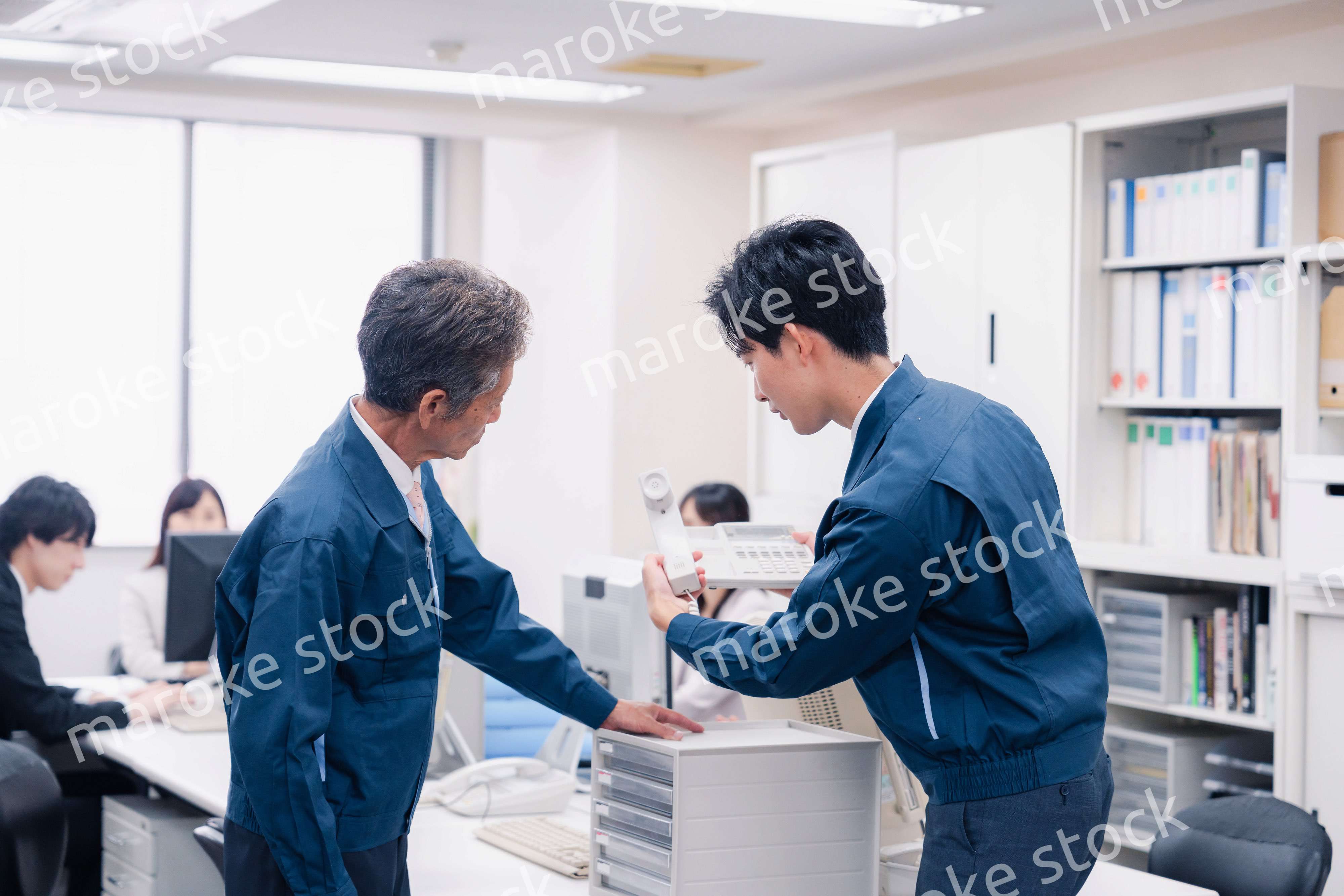 オフィスで電話機のメンテナンスをする作業員の男性