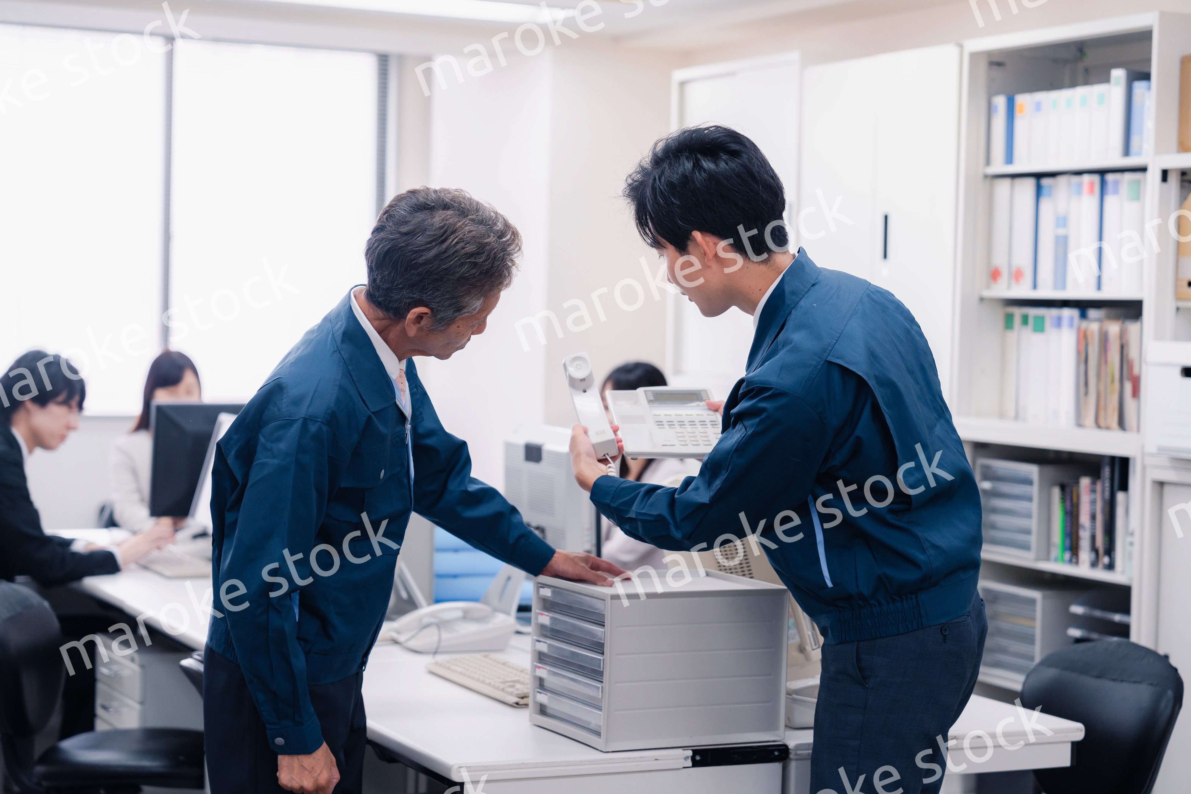 オフィスで電話機のメンテナンスをする作業員の男性