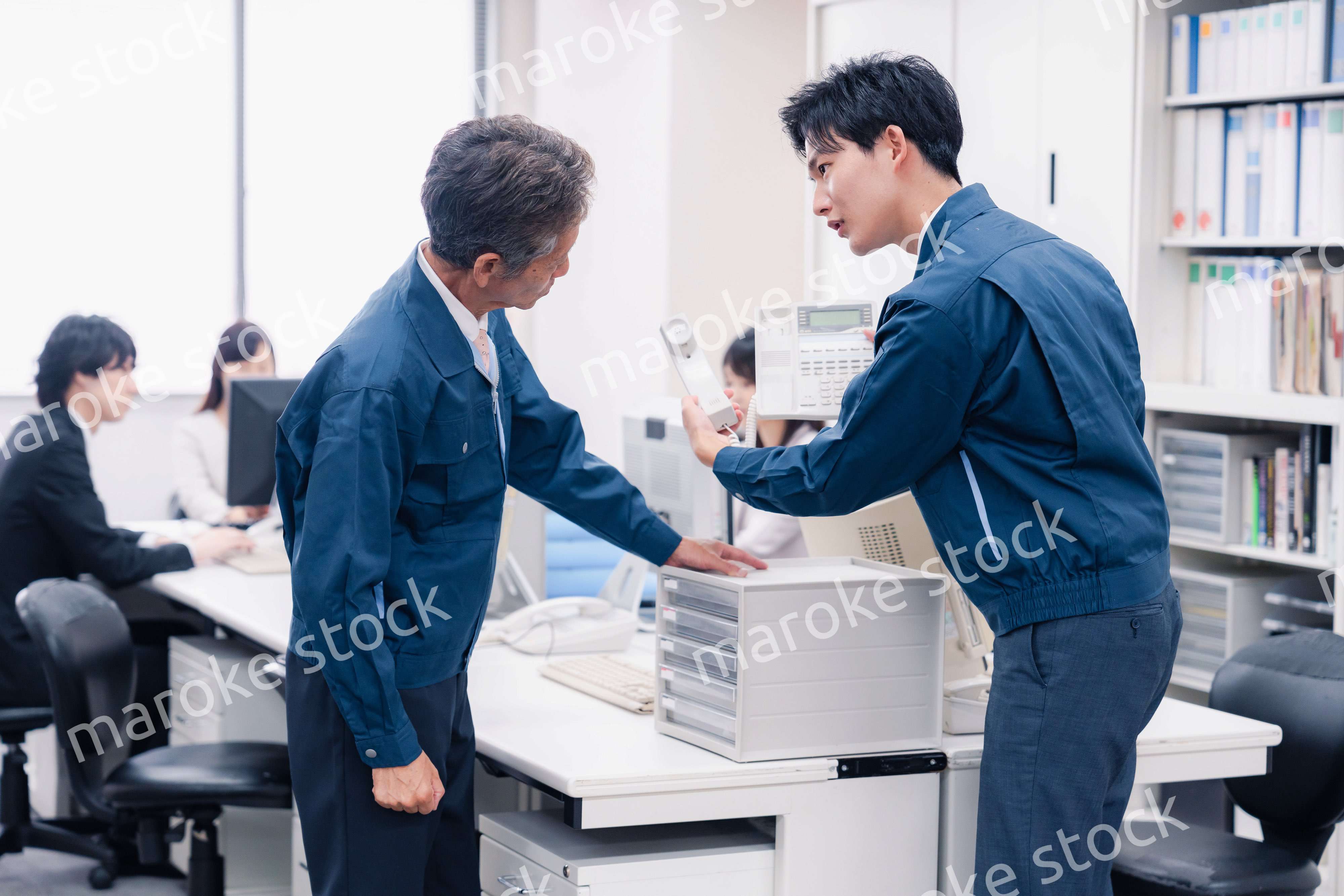 オフィスで電話機のメンテナンスをする作業員の男性