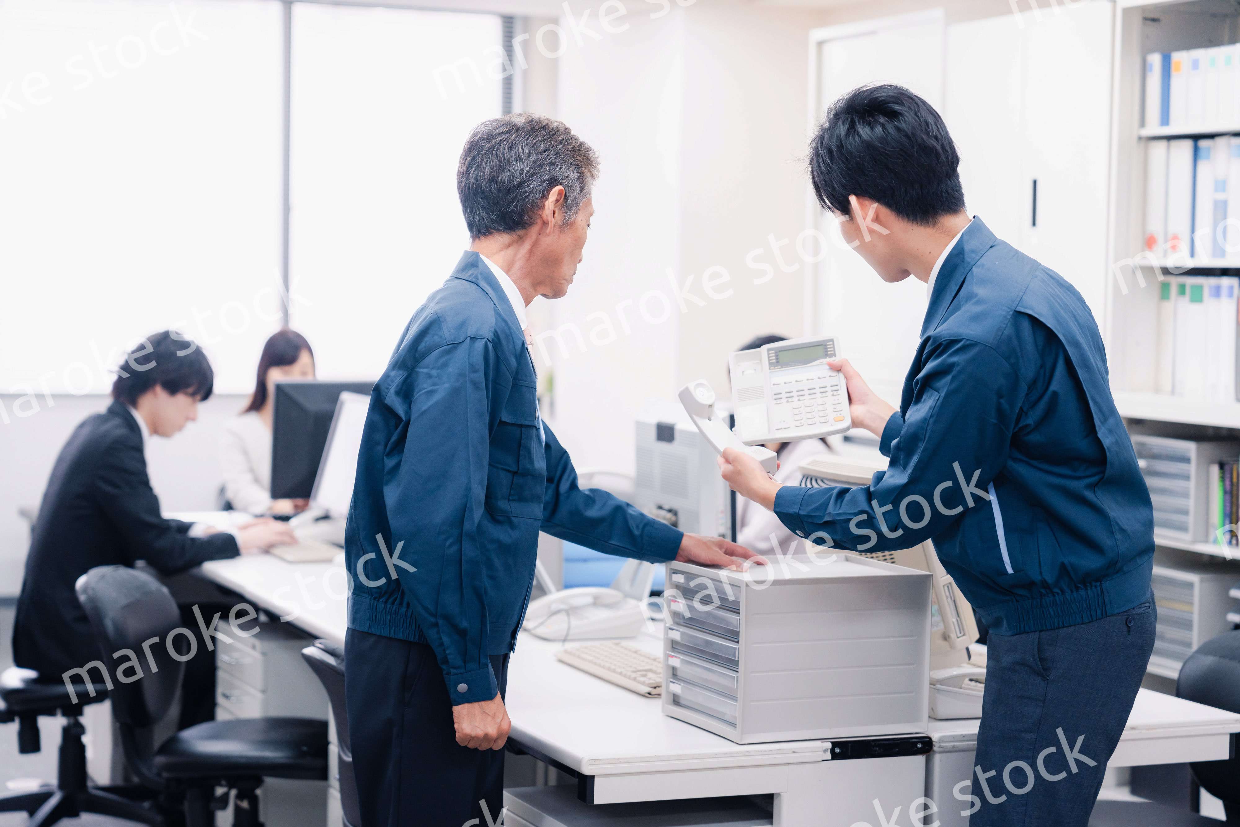 オフィスで電話機のメンテナンスをする作業員の男性