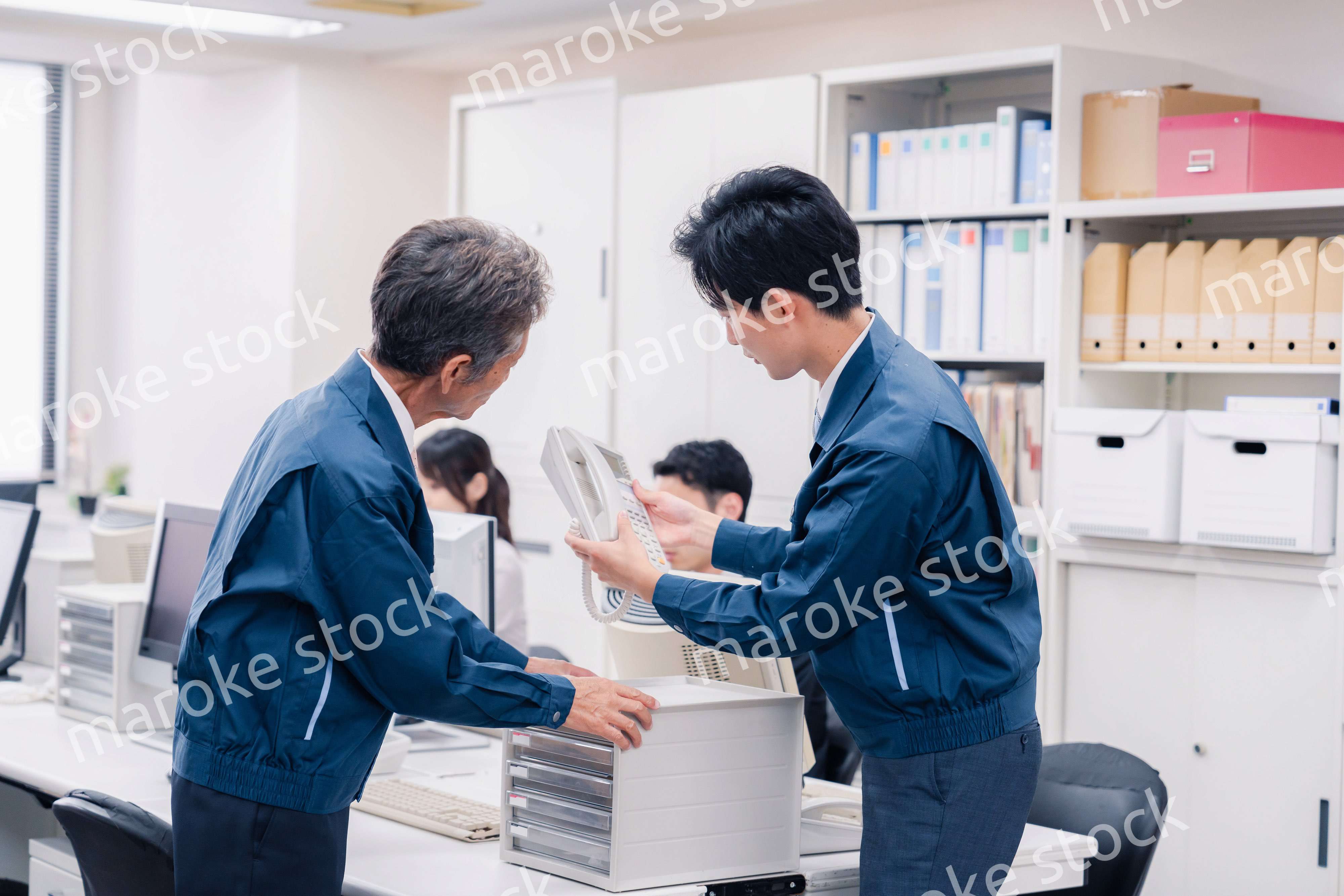 オフィスで電話機のメンテナンスをする作業員の男性