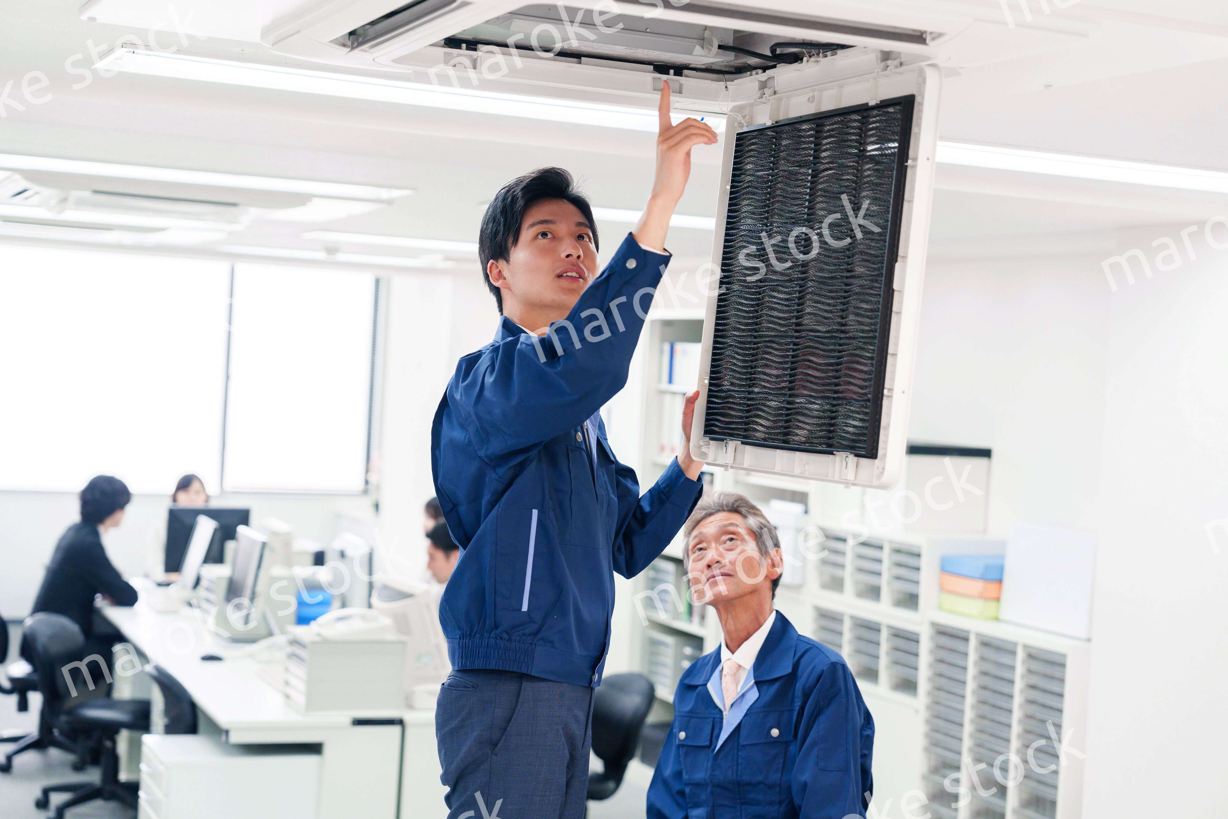 ビルのエアコンの点検をする作業服の男性