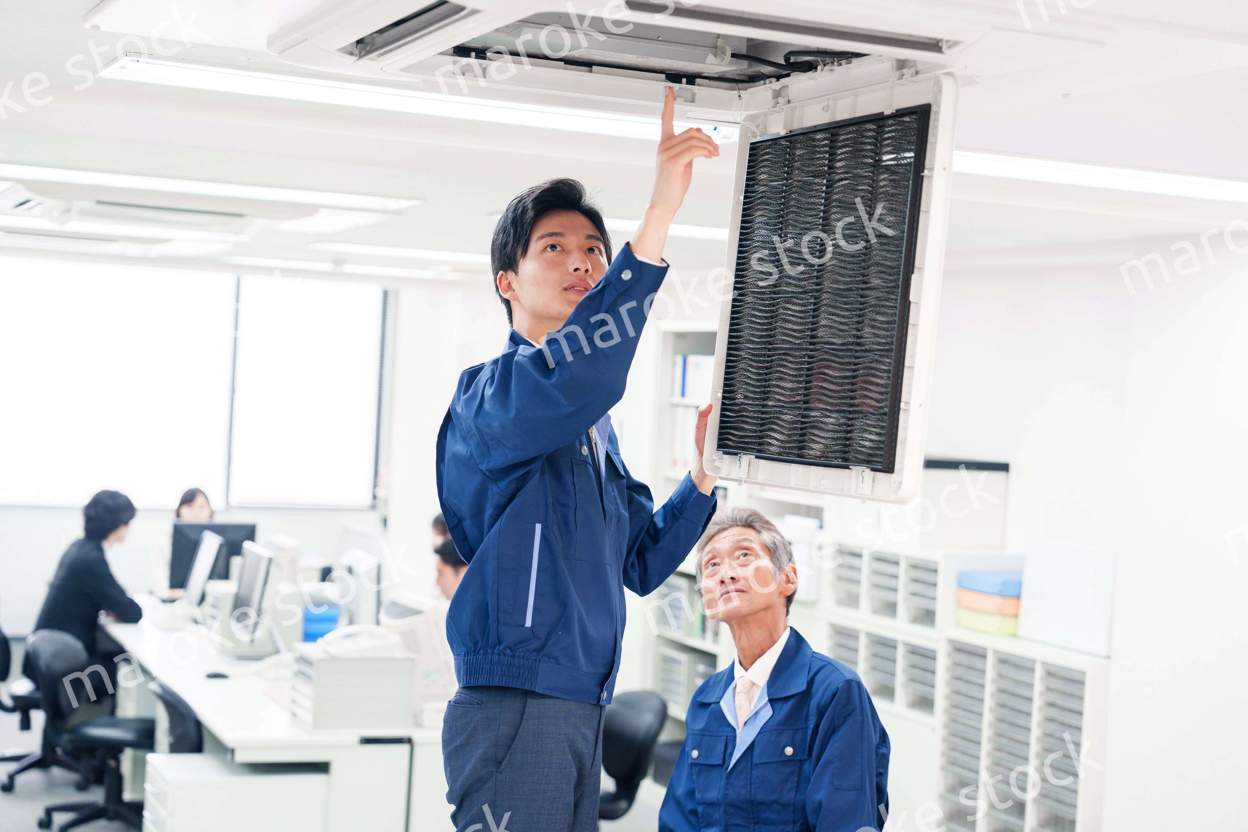 ビルのエアコンの点検をする作業服の男性