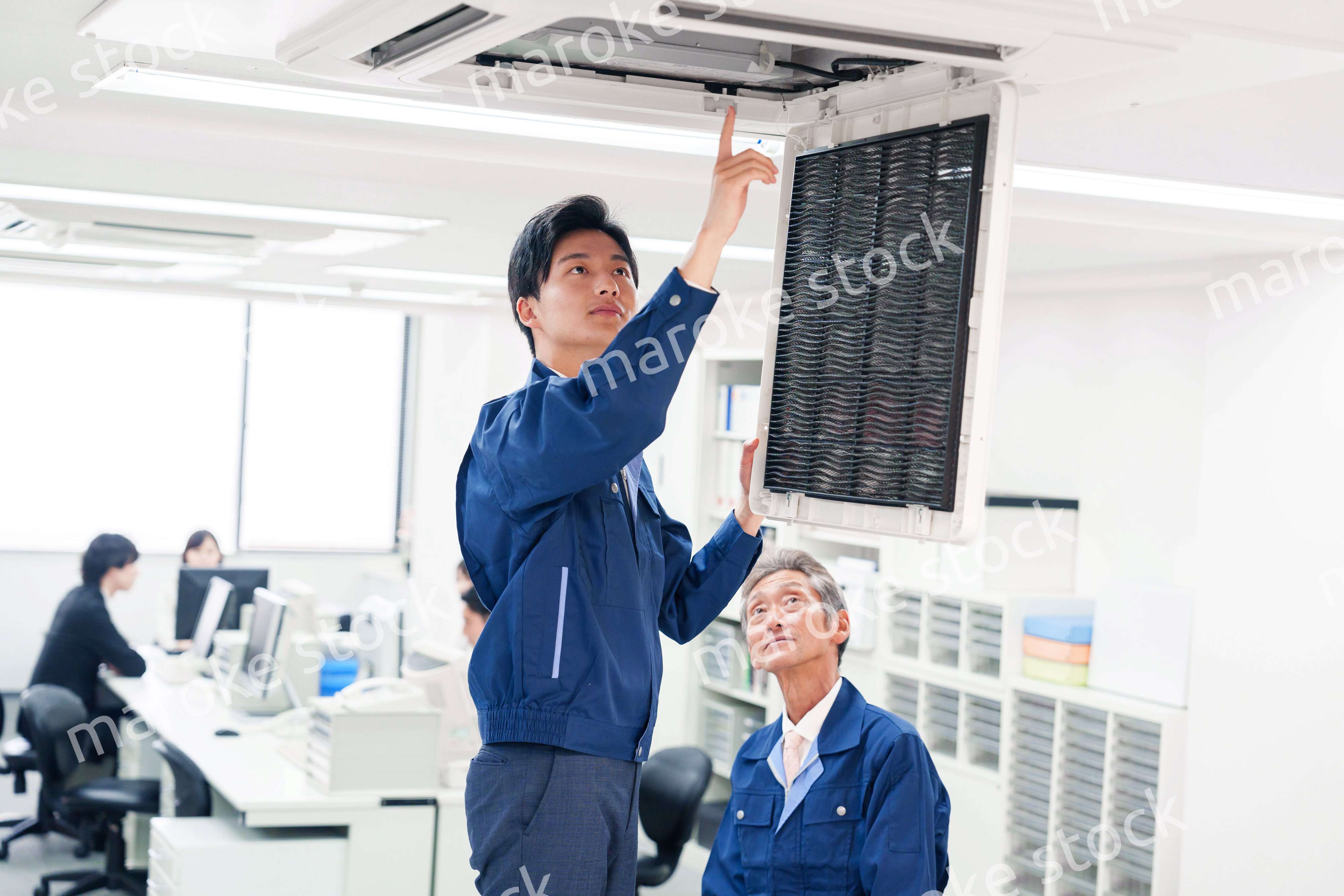 ビルのエアコンの点検をする作業服の男性