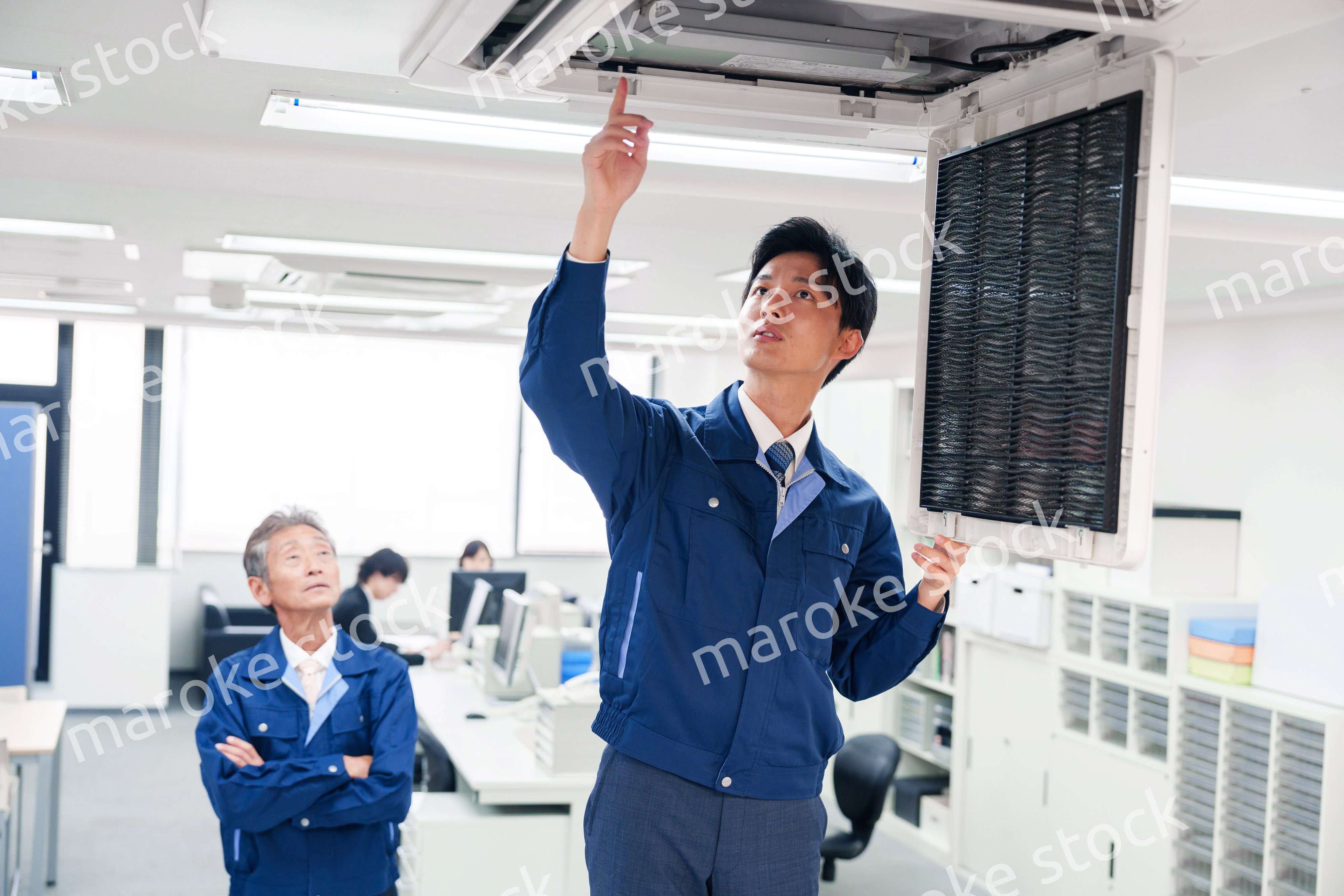 ビルのエアコンの点検をする作業服の男性