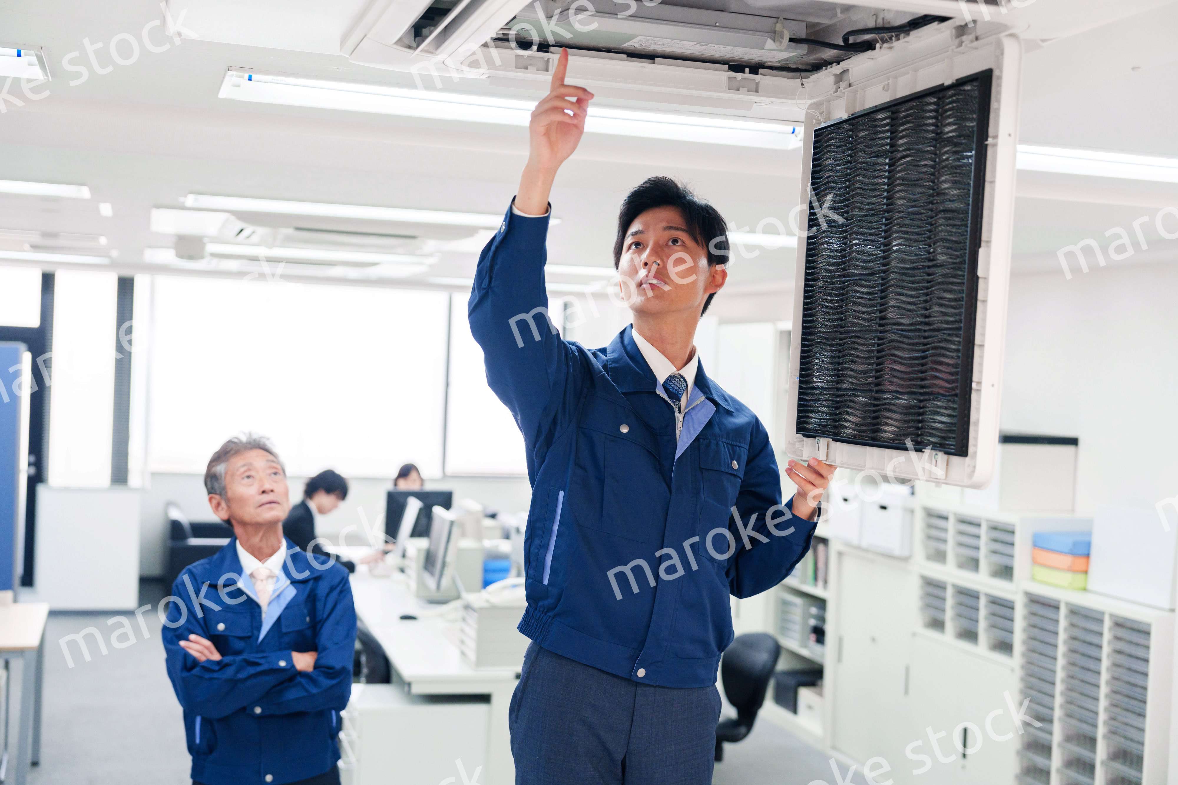 ビルのエアコンの点検をする作業服の男性