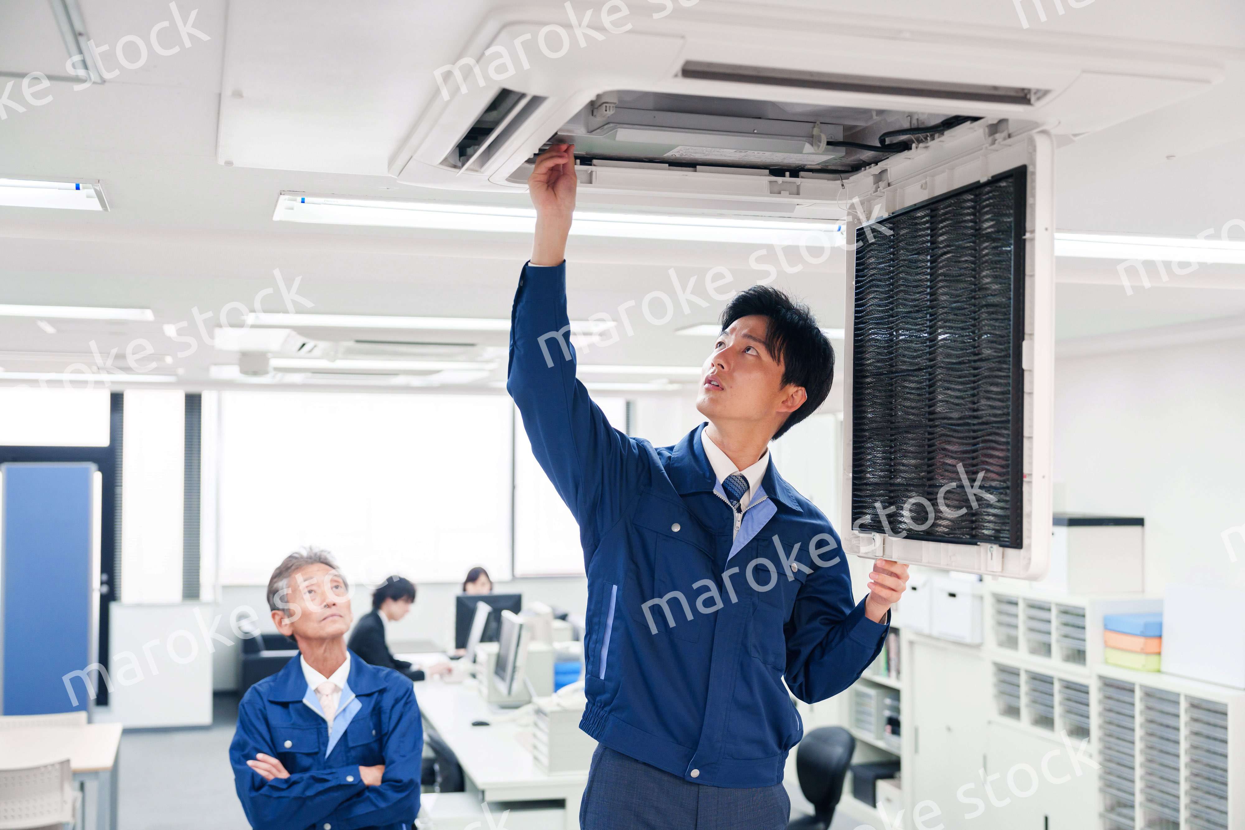 ビルのエアコンの点検をする作業服の男性