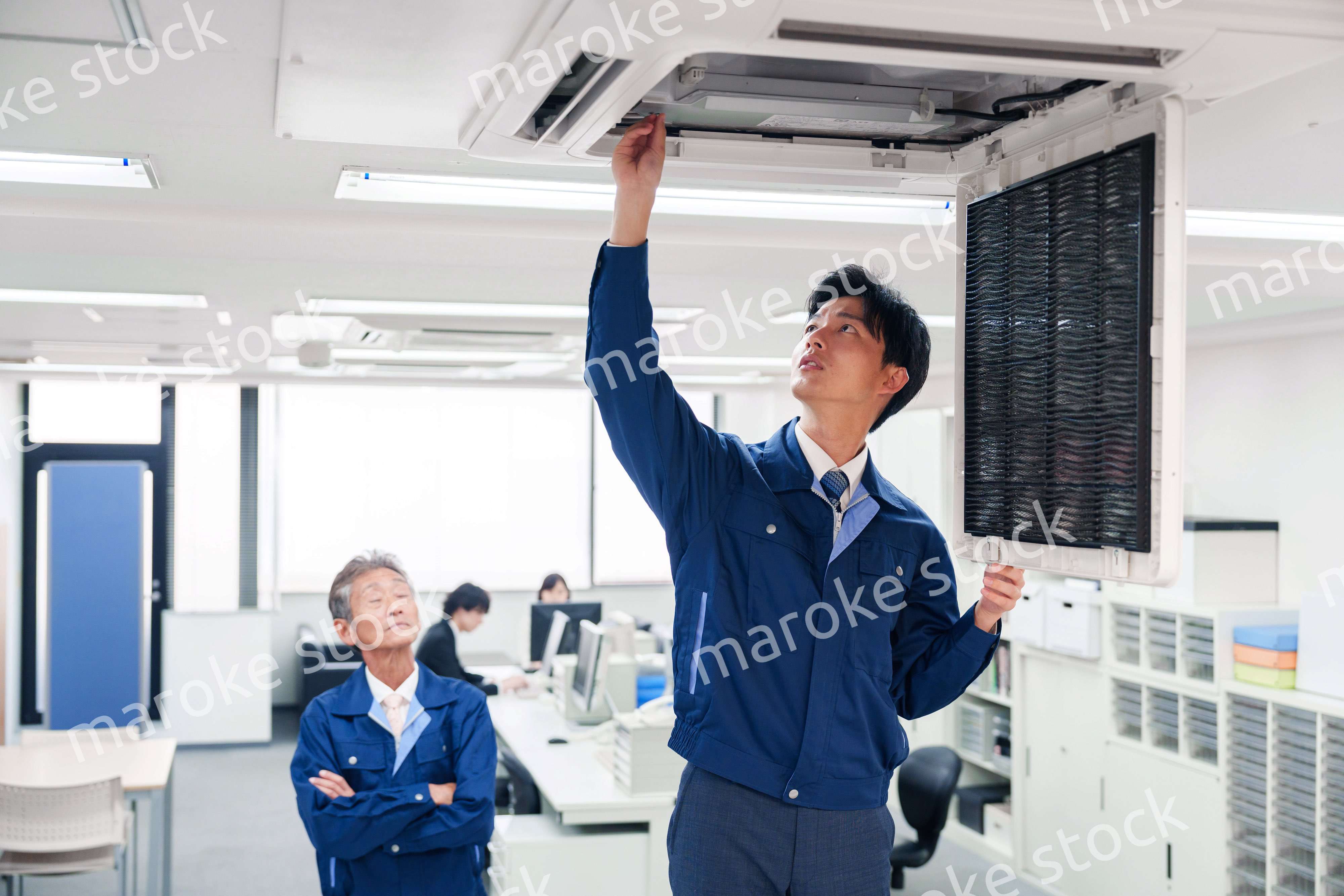 ビルのエアコンの点検をする作業服の男性