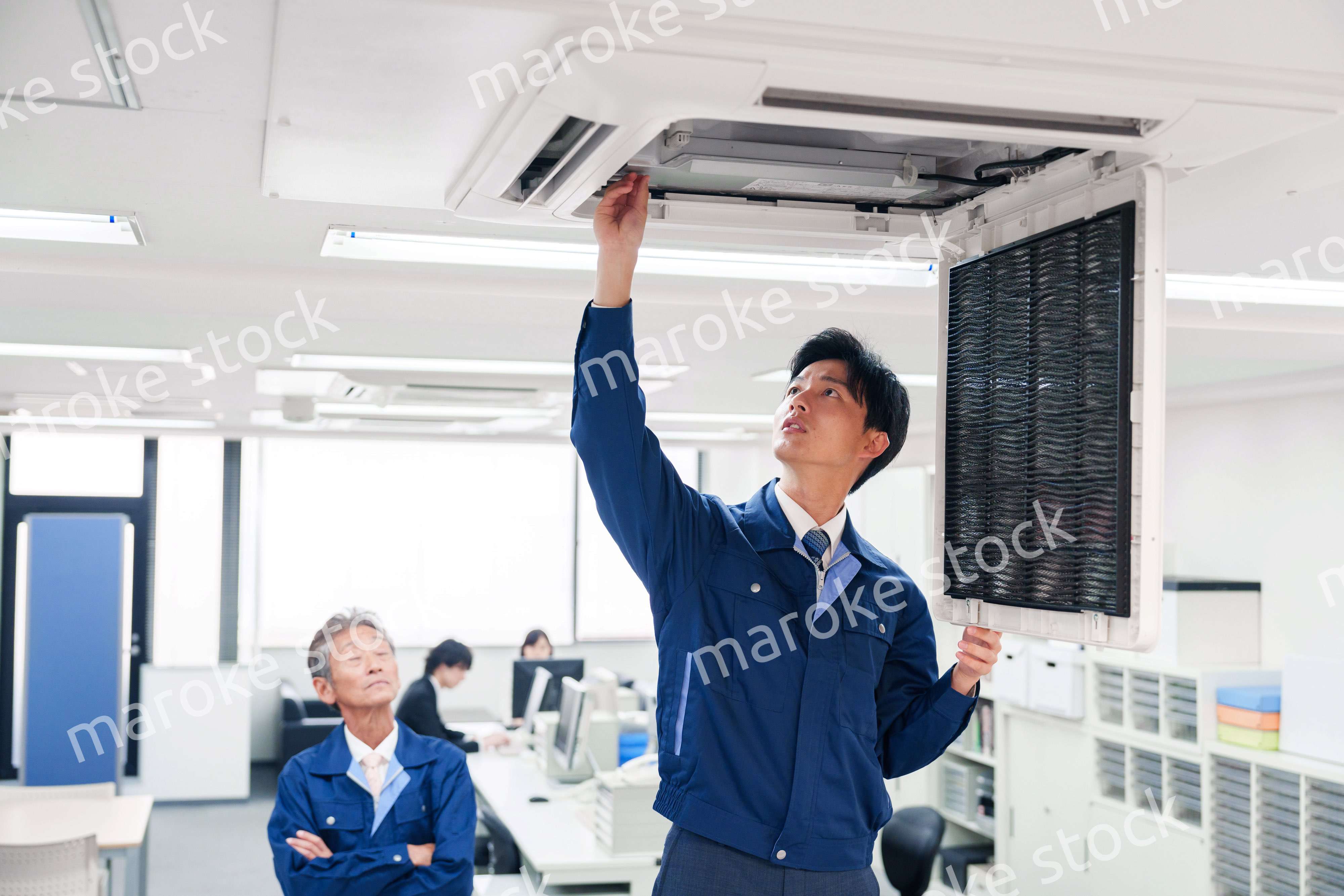 ビルのエアコンの点検をする作業服の男性