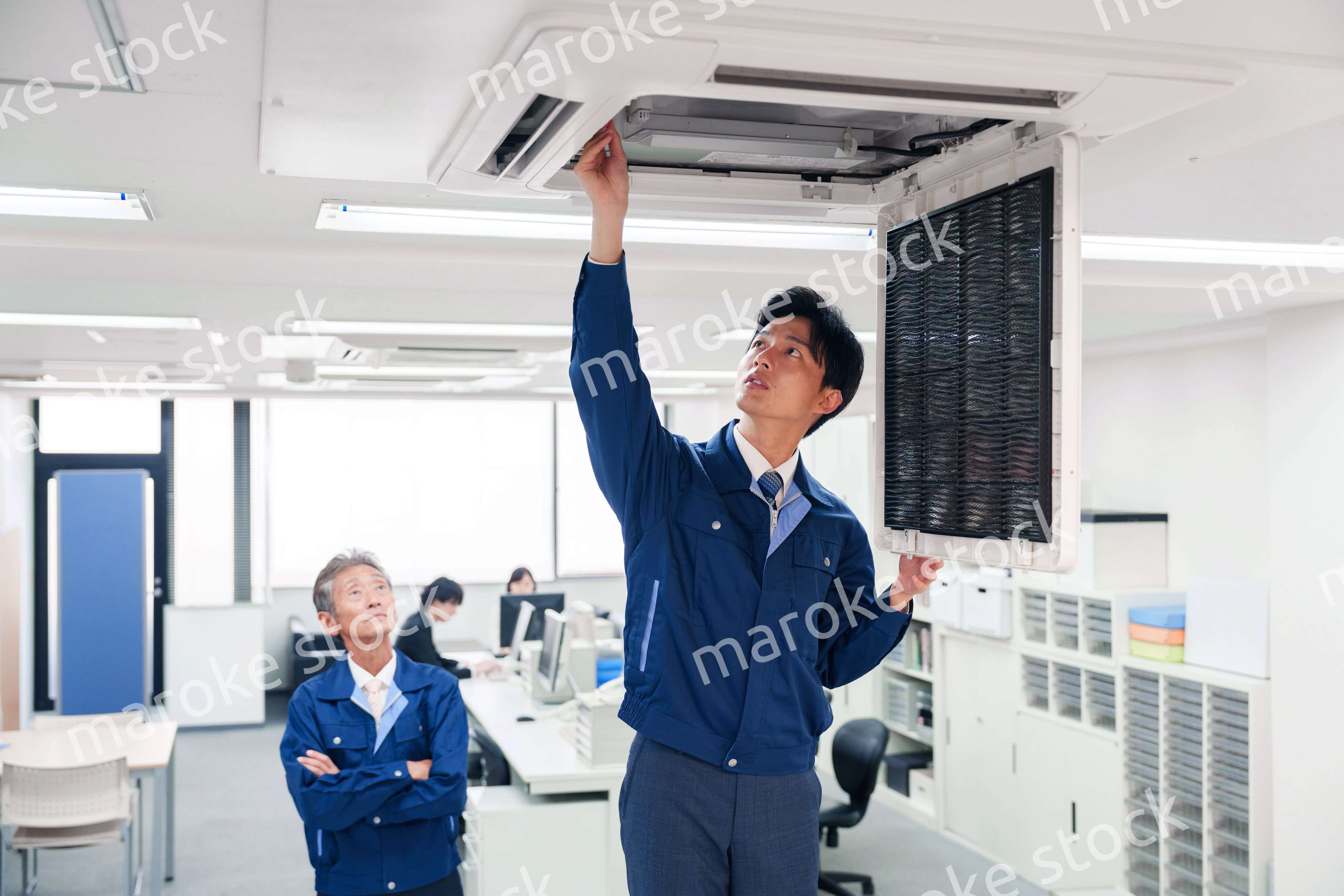 ビルのエアコンの点検をする作業服の男性