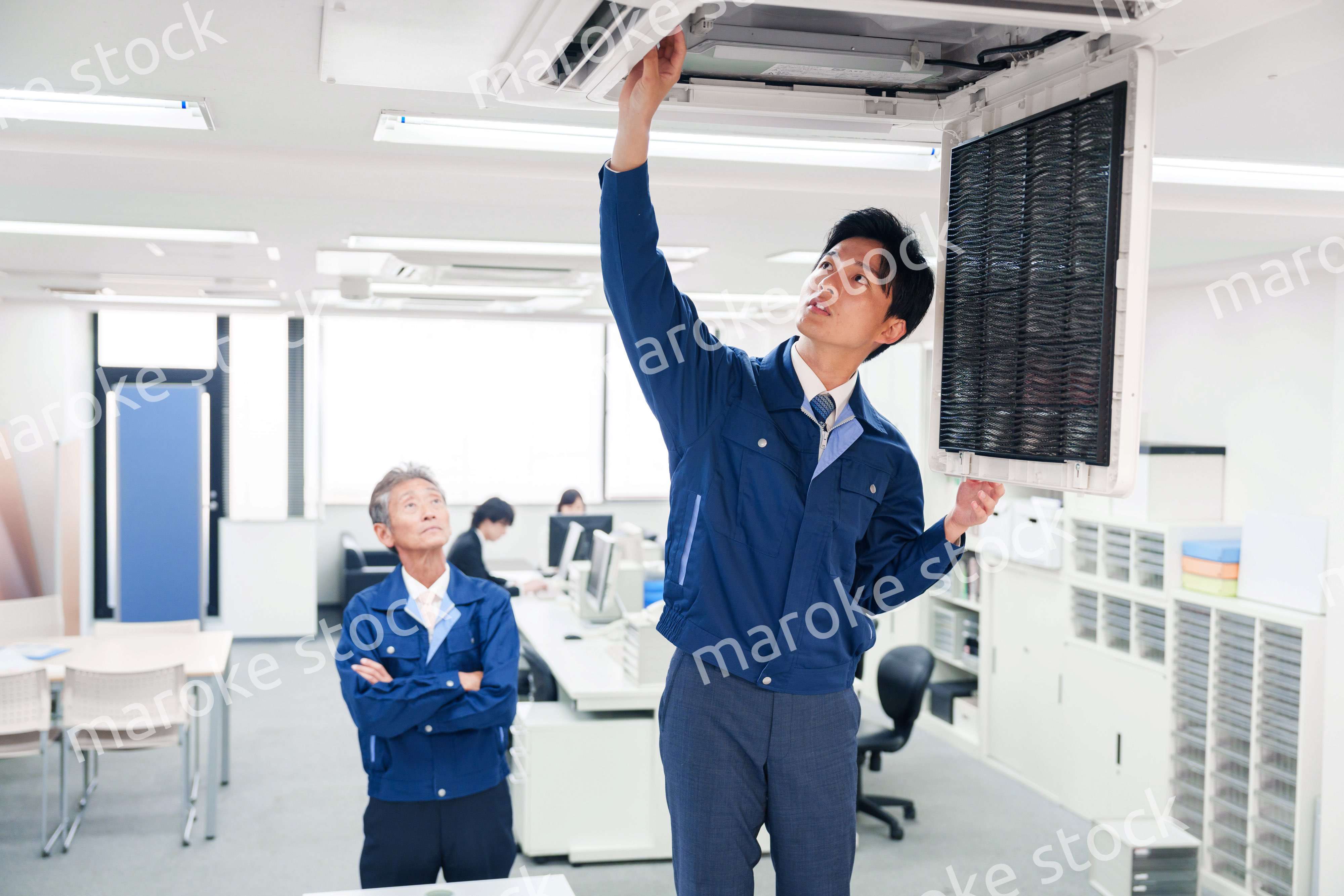 ビルのエアコンの点検をする作業服の男性