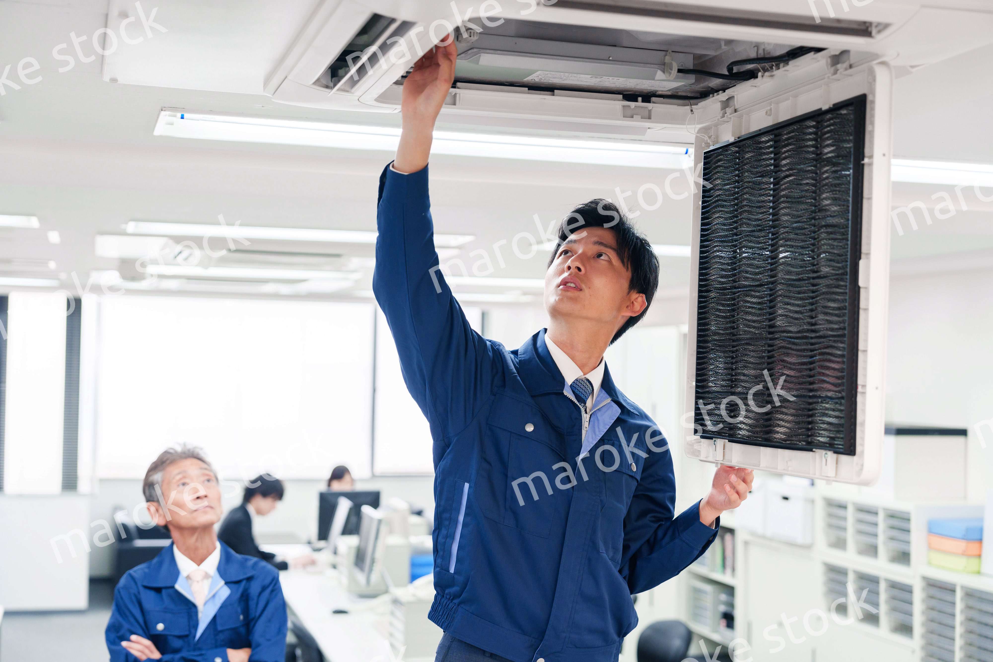 ビルのエアコンの点検をする作業服の男性