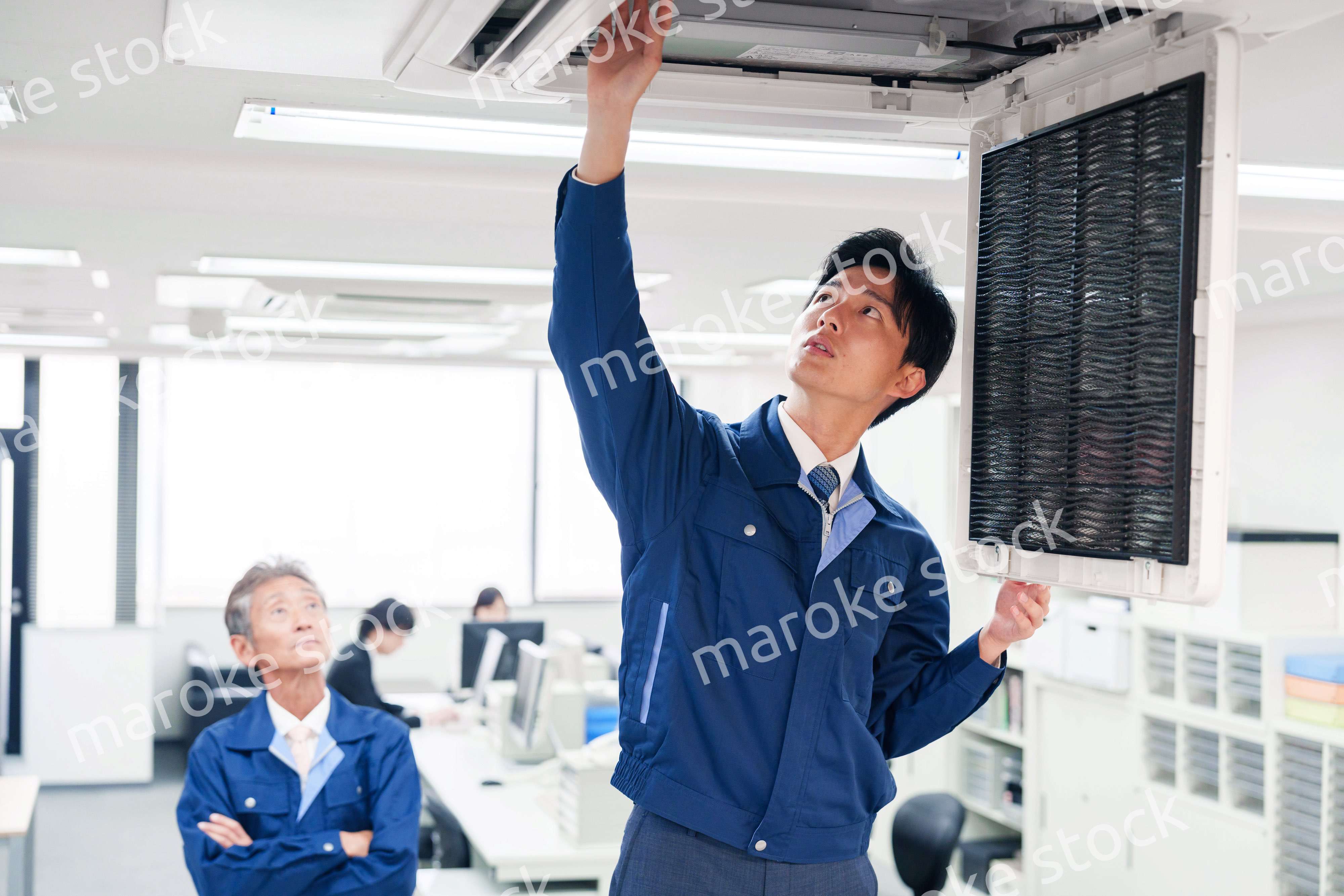 ビルのエアコンの点検をする作業服の男性